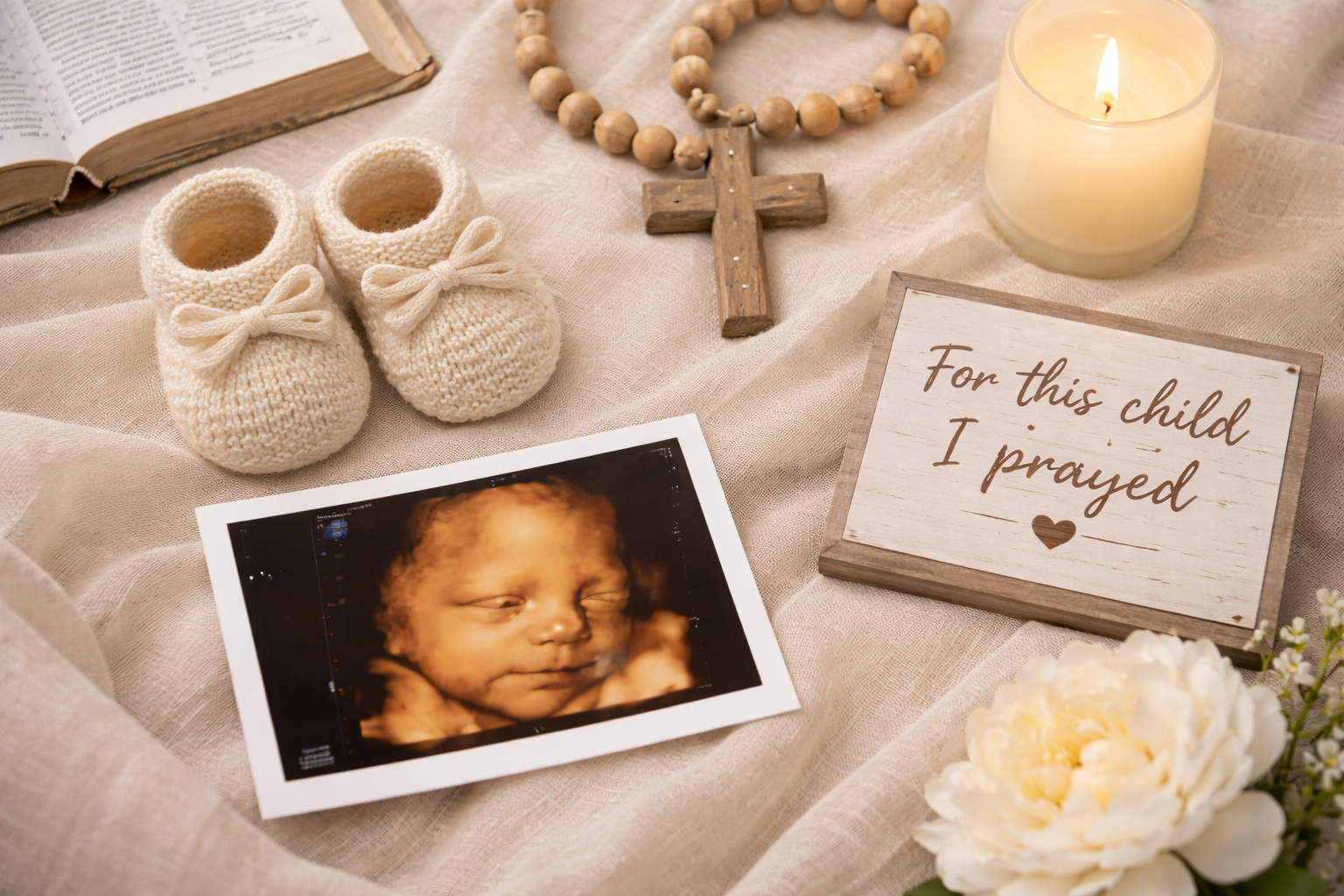 3D ultrasound baby image displayed with knitted baby shoes, a wooden cross, a Bible, and a “For This Child I Prayed” card at Miracles On Main Sono in West Point Mississippi