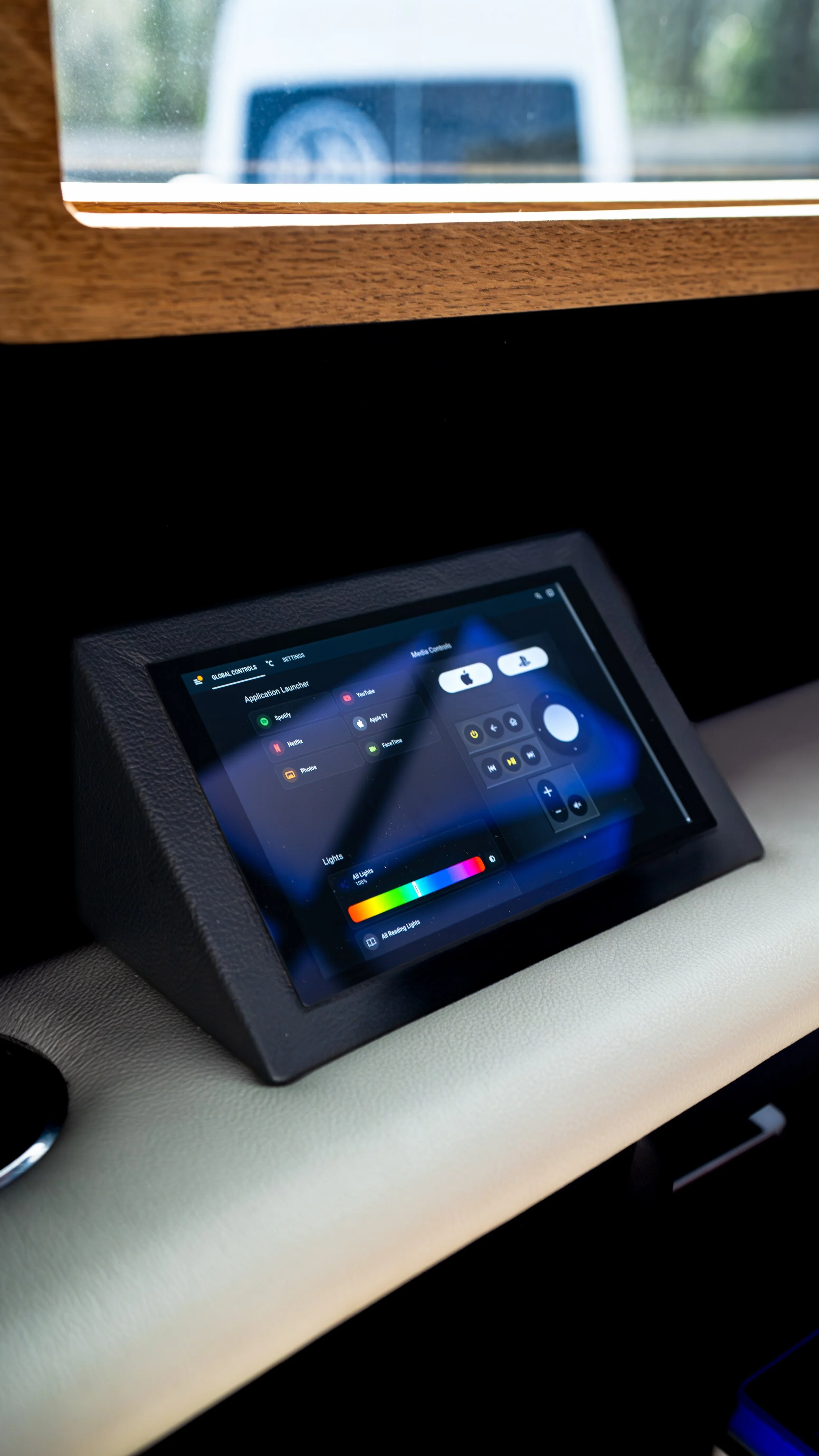 Interior of a vehicle showing a touchscreen control panel with various application icons and lighting controls.