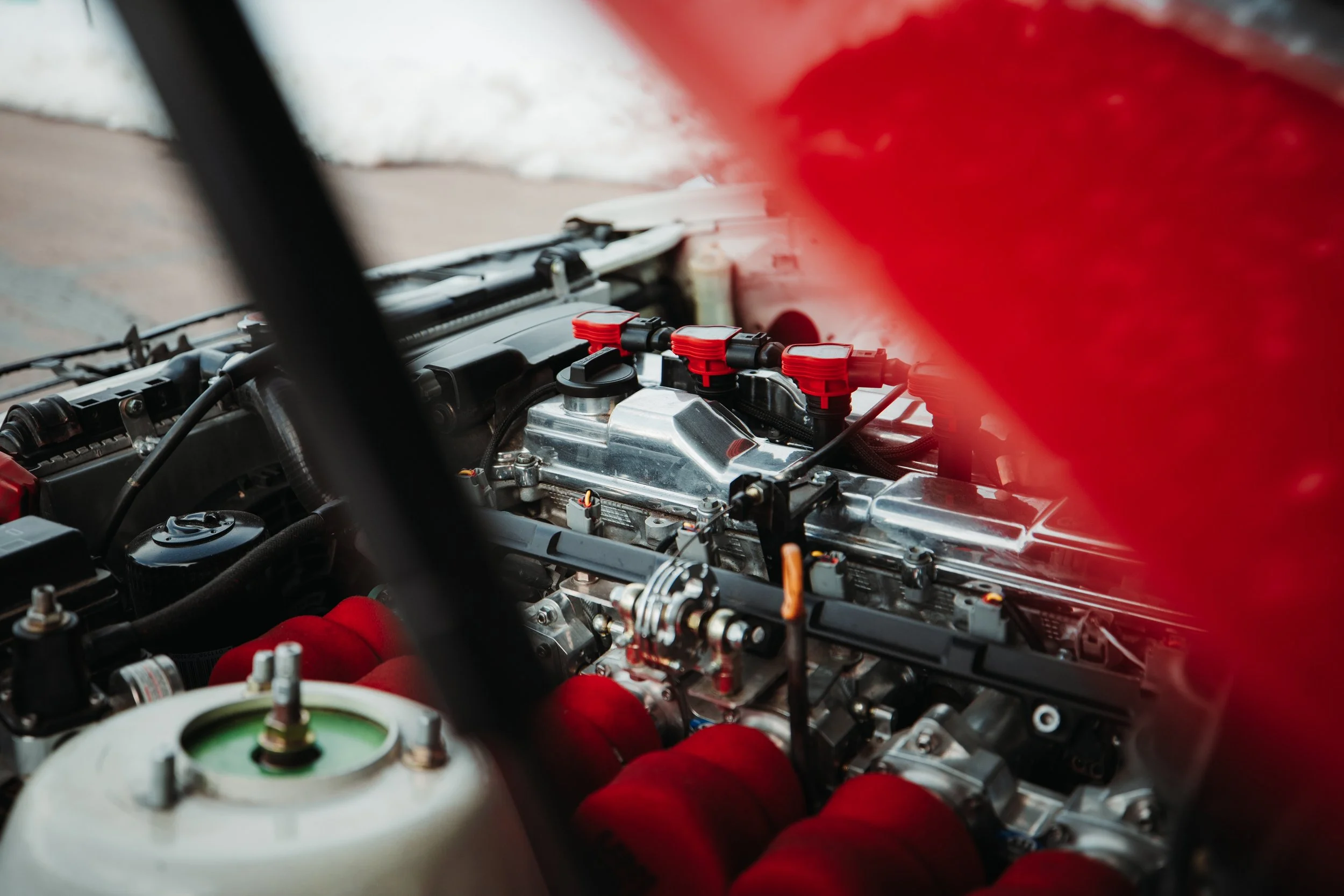 Close-up of a race car engine with red ignition wires and other metallic components.