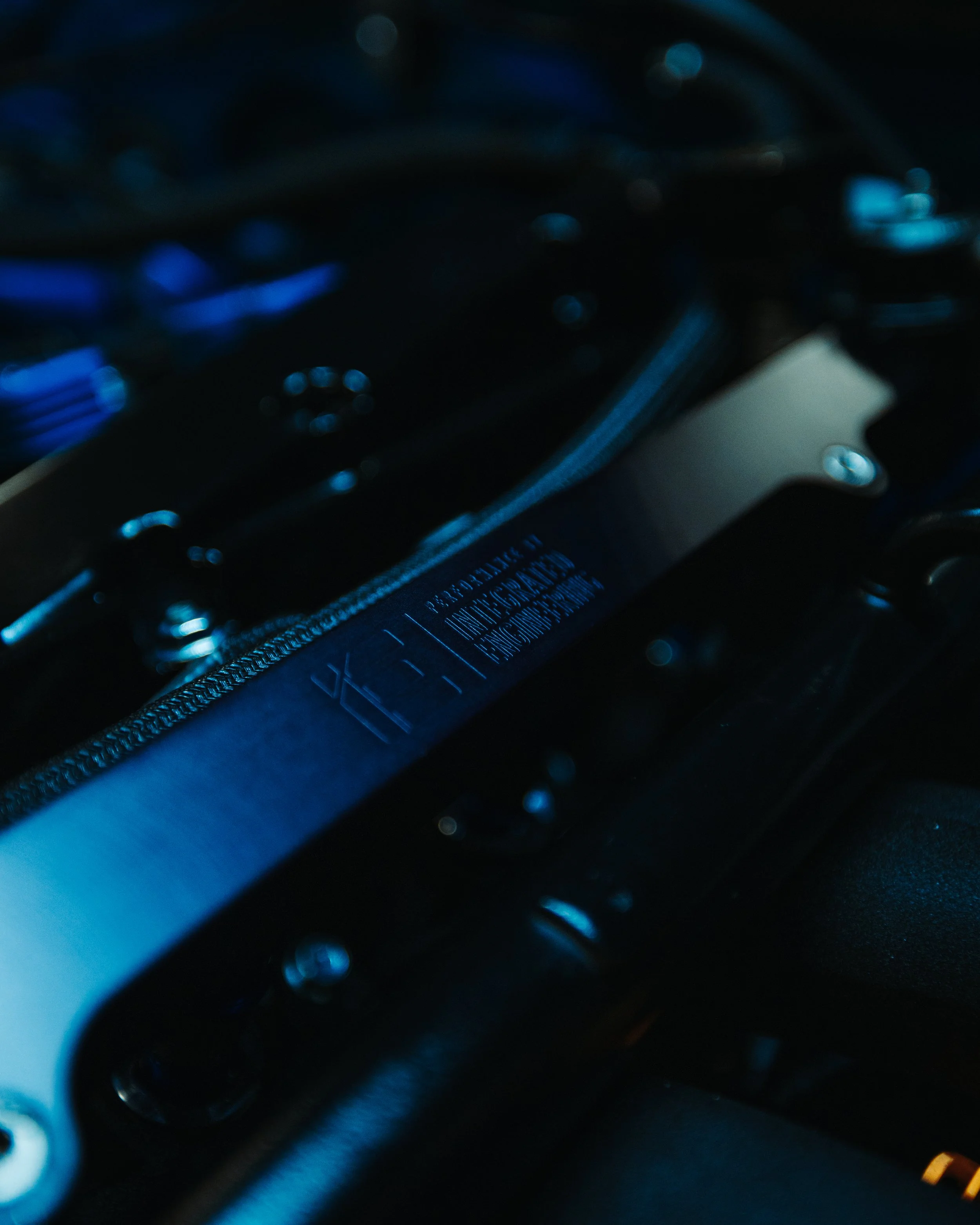 Close-up of a car engine part with metallic and black components illuminated by blue light.