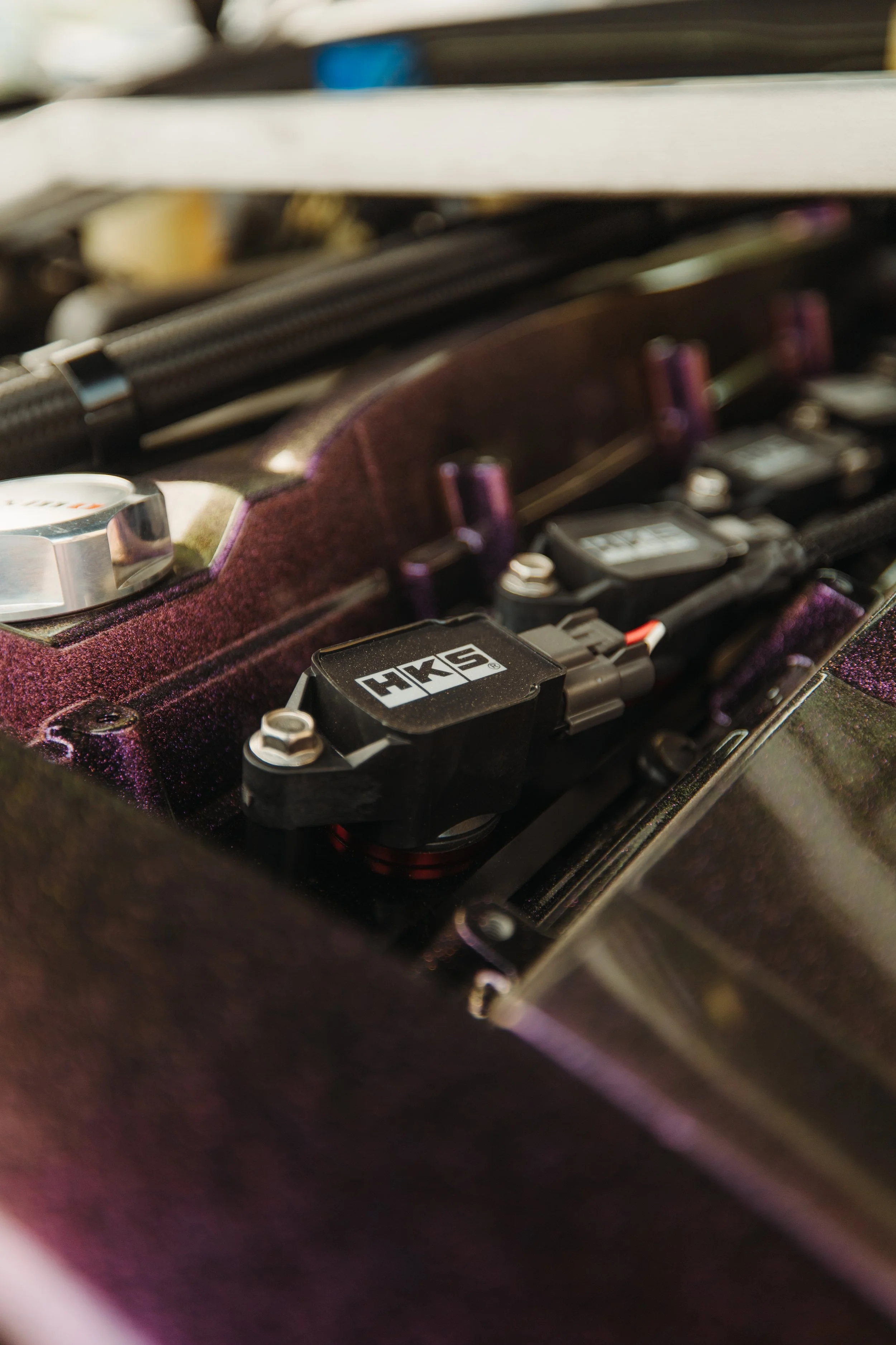 Close-up view of a racing car engine with a focus on a black component labeled 'HKS'.