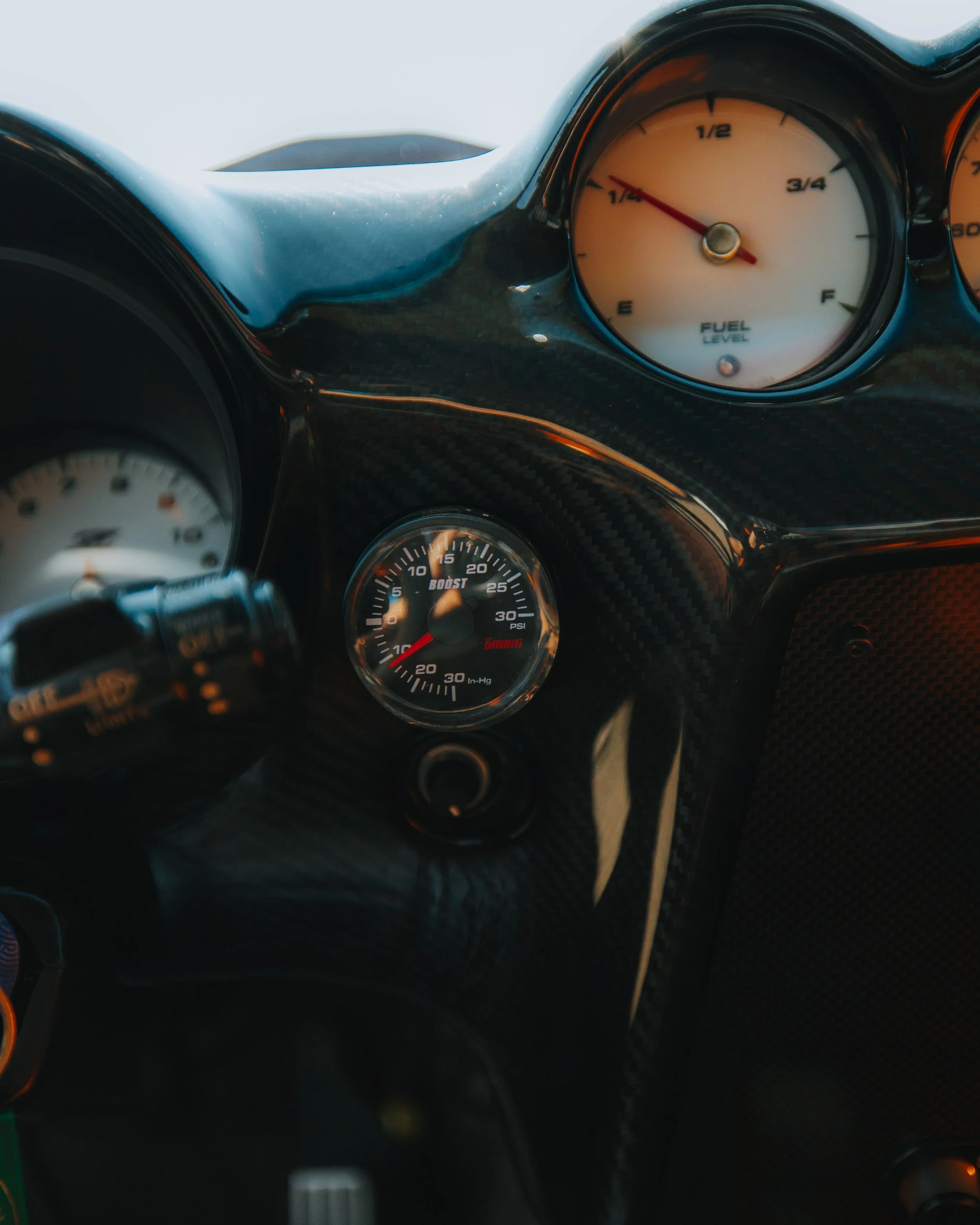 Close-up of a car dashboard with gauges showing fuel level, boost pressure, and other metrics.