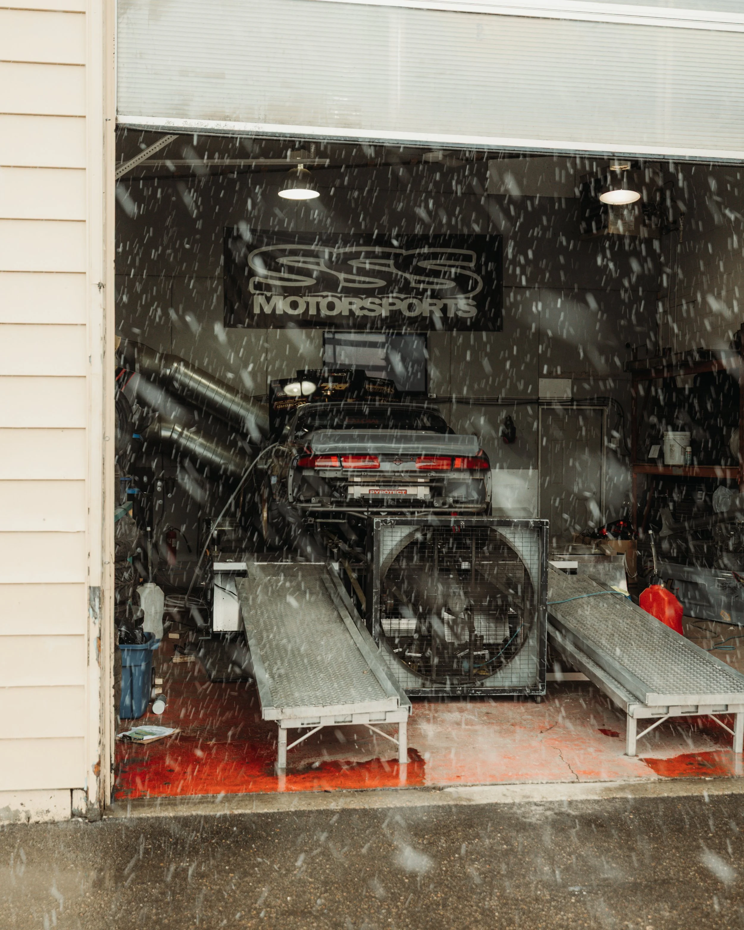 Car on dynamometer inside S&S Motorsports garage during rain