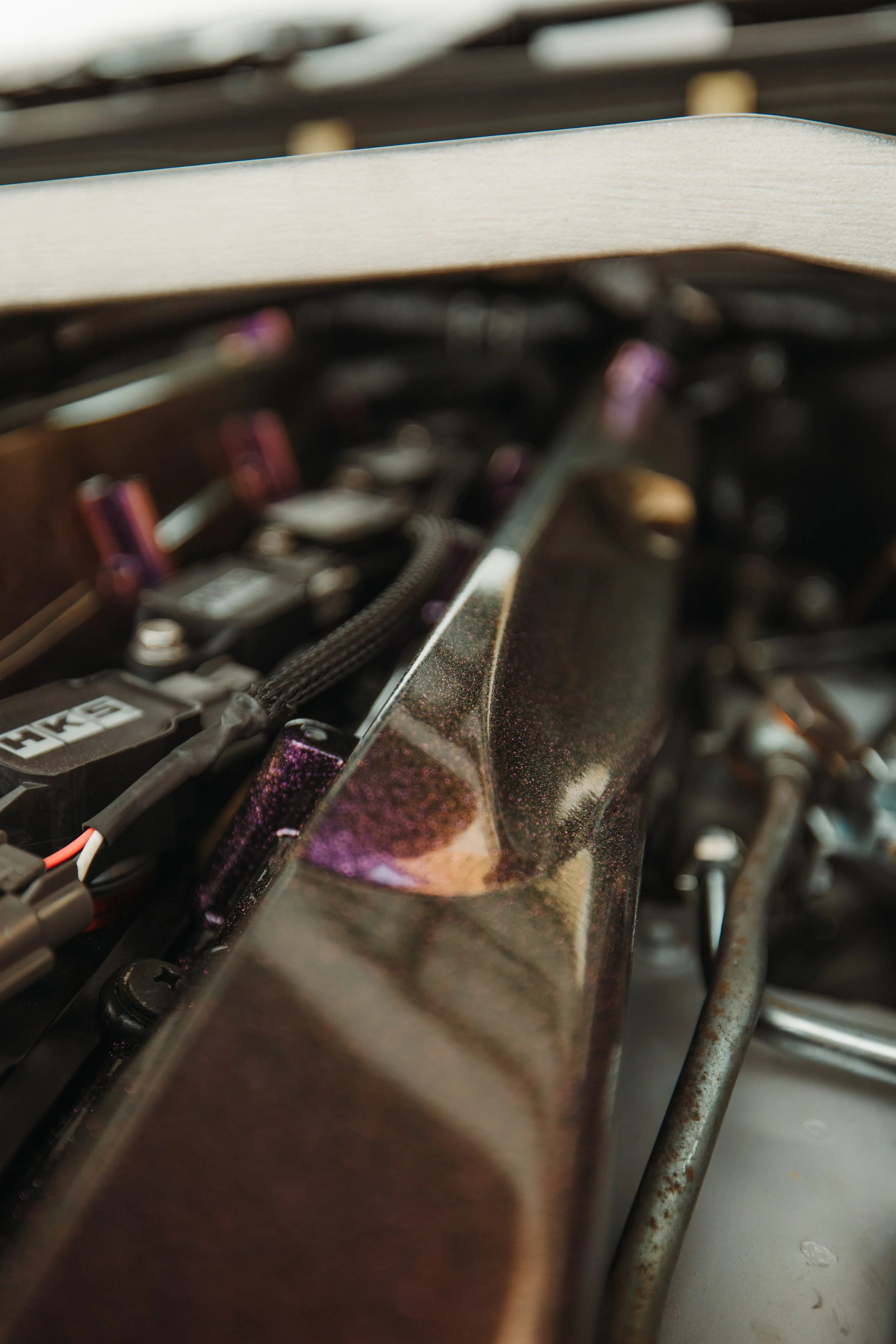 Close-up of a metallic engine component with purple accents and a wooden element on top.