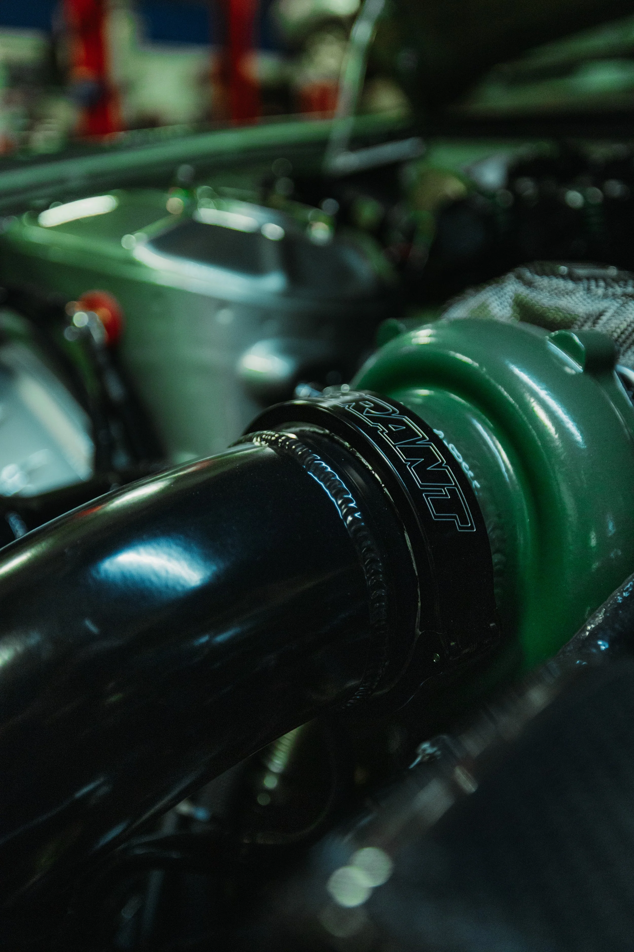 Close-up of a motocross bike suspension with a black fork and green shock absorber, inside a garage or workshop.