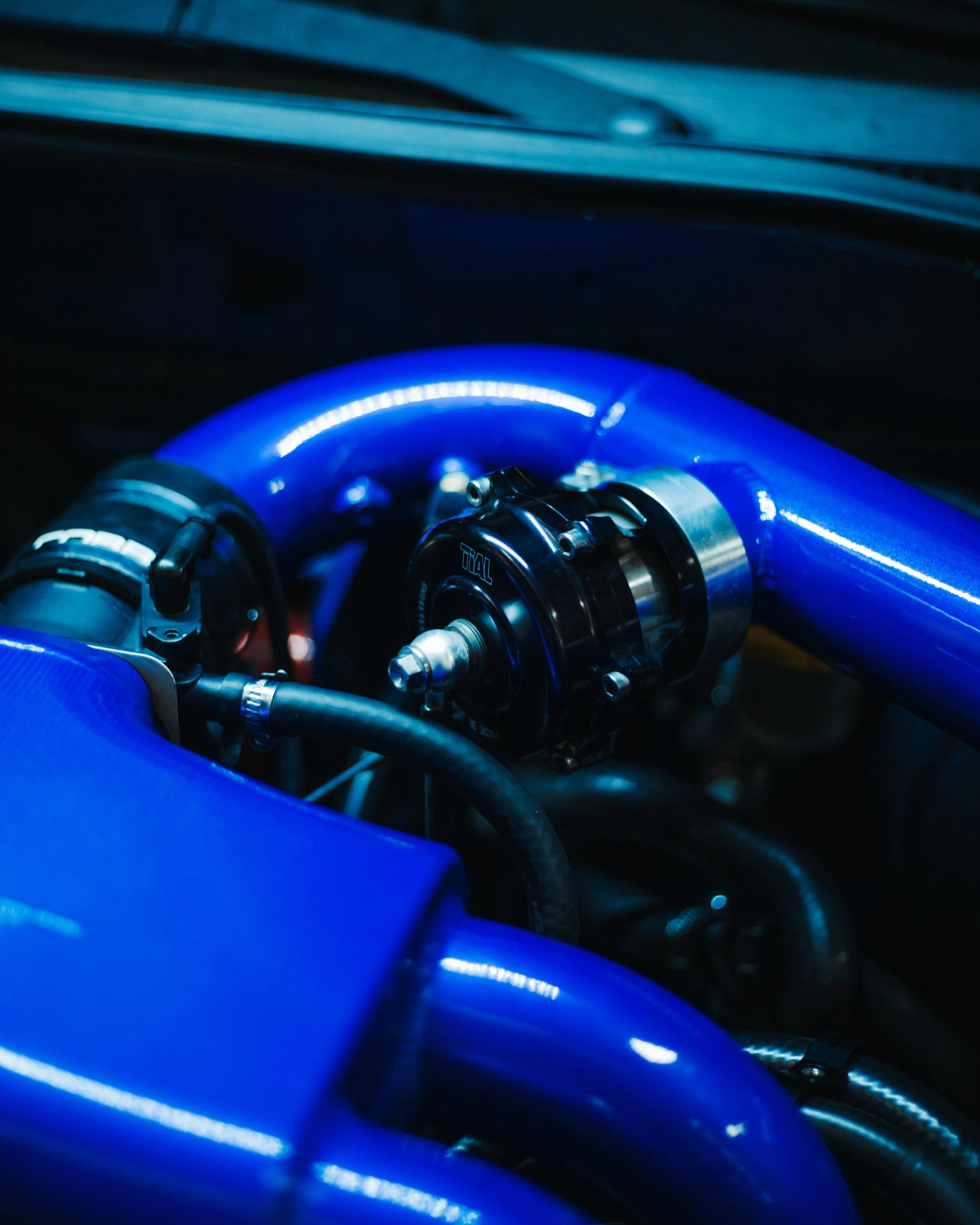 Close-up of a blue automotive intake pipe and black turbocharger component inside a car engine.