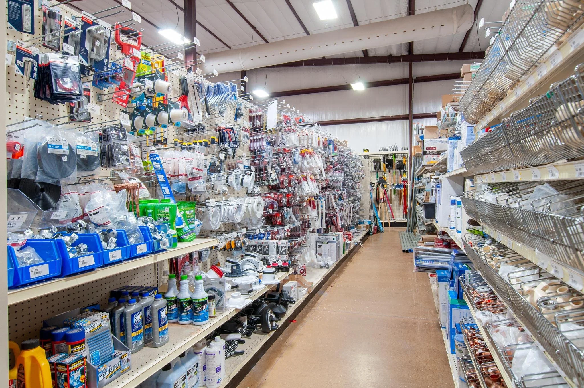 Tile aisle in a hardware store with various tools and supplies, including paint, cleaning supplies, and hardware accessories.