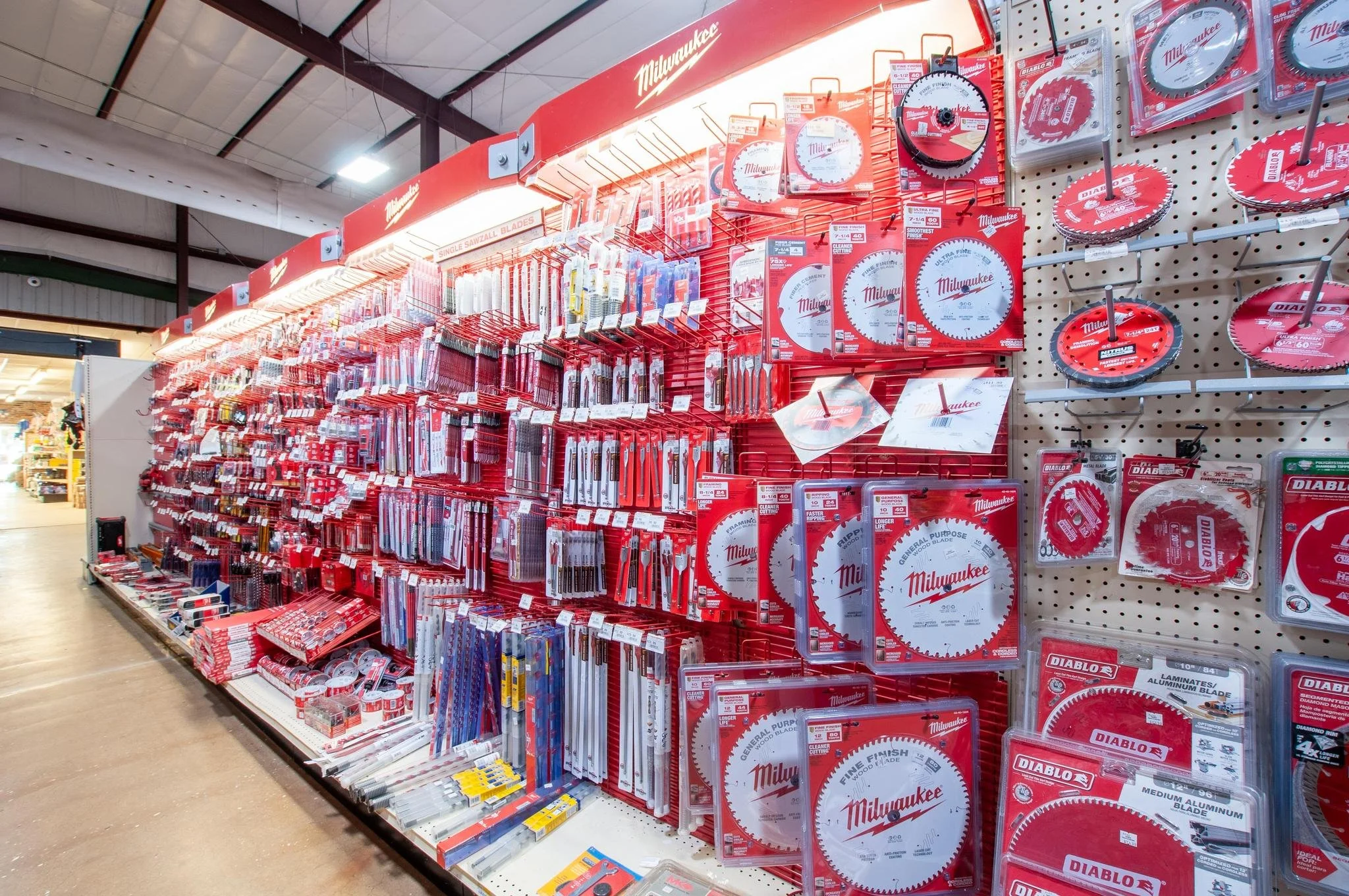 A display of Milwaukee brand circular saw blades and blades on a pegboard in a hardware store.