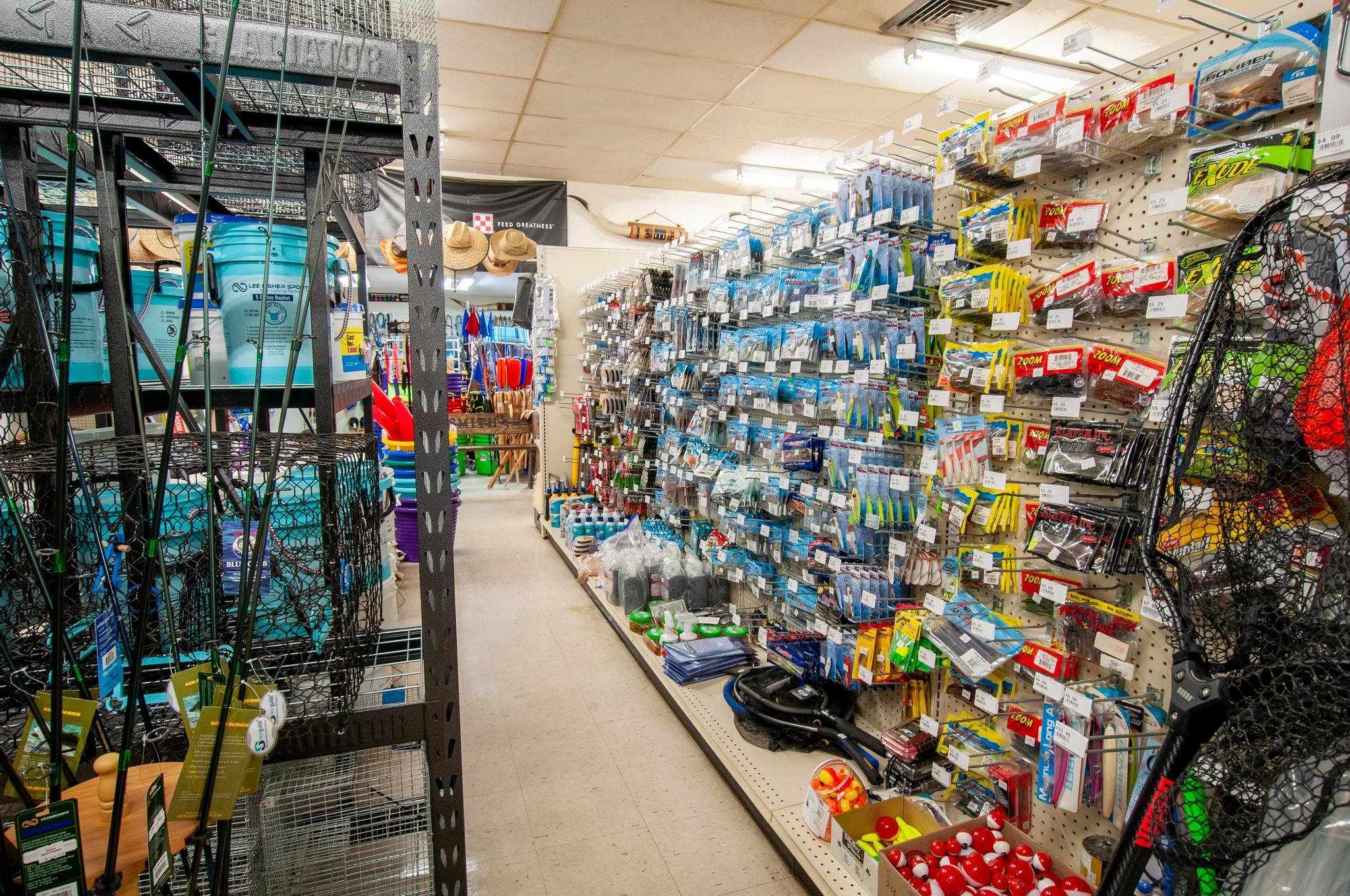 Aisle in a sporting goods store with various fishing accessories and equipment on shelves, including fishing lures, hooks, and other fishing gear.