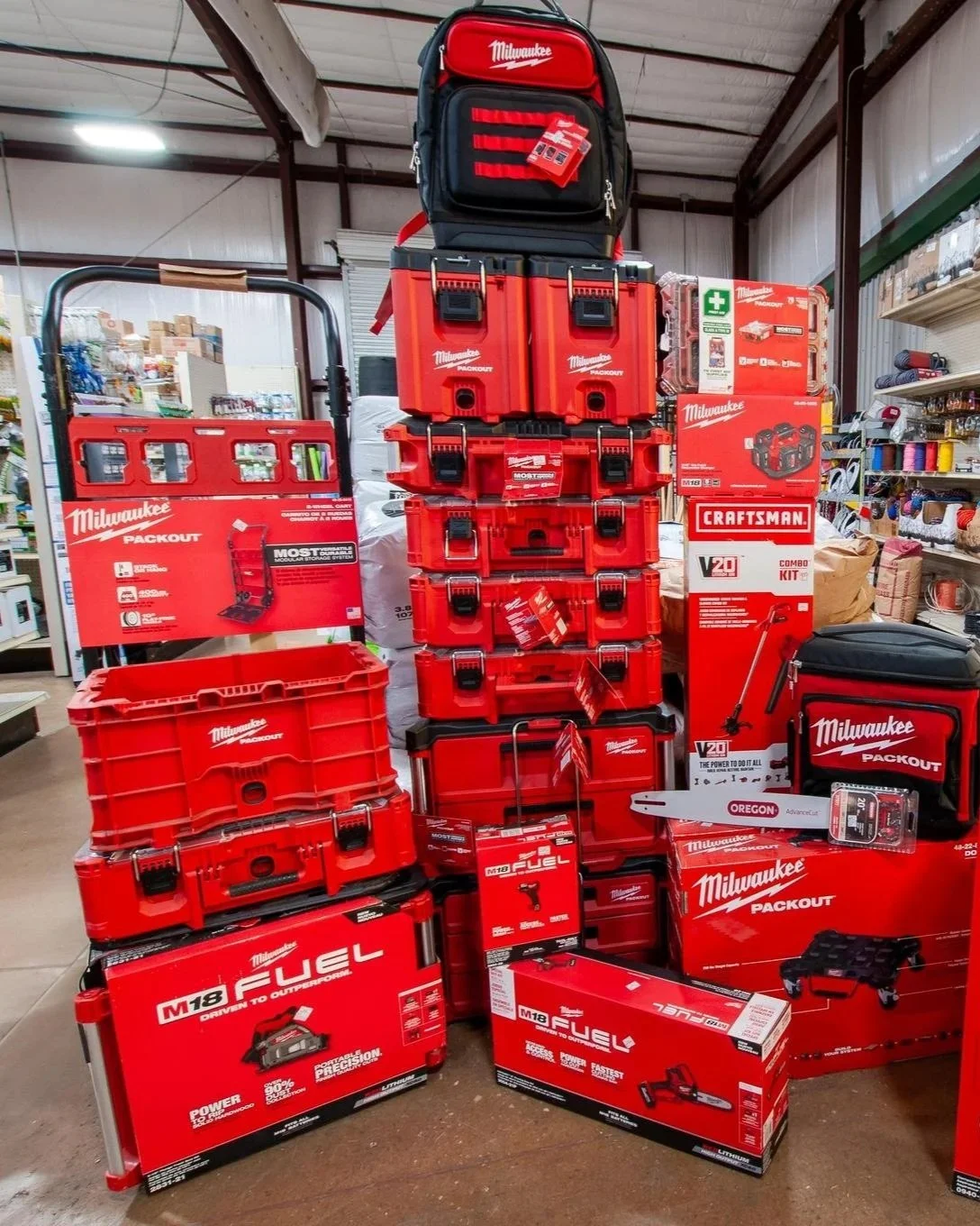 Display of Milwaukee power tools and storage cases, including tool bags, boxes, and accessories, at a hardware store.