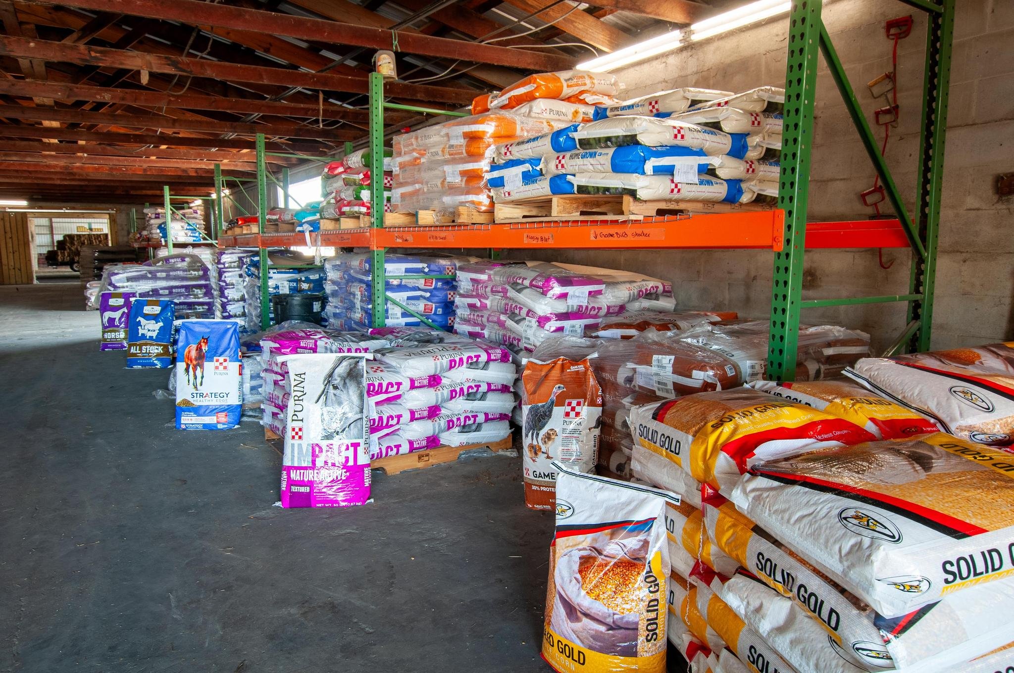 Shelves stocked with various bags of pet food in a warehouse.