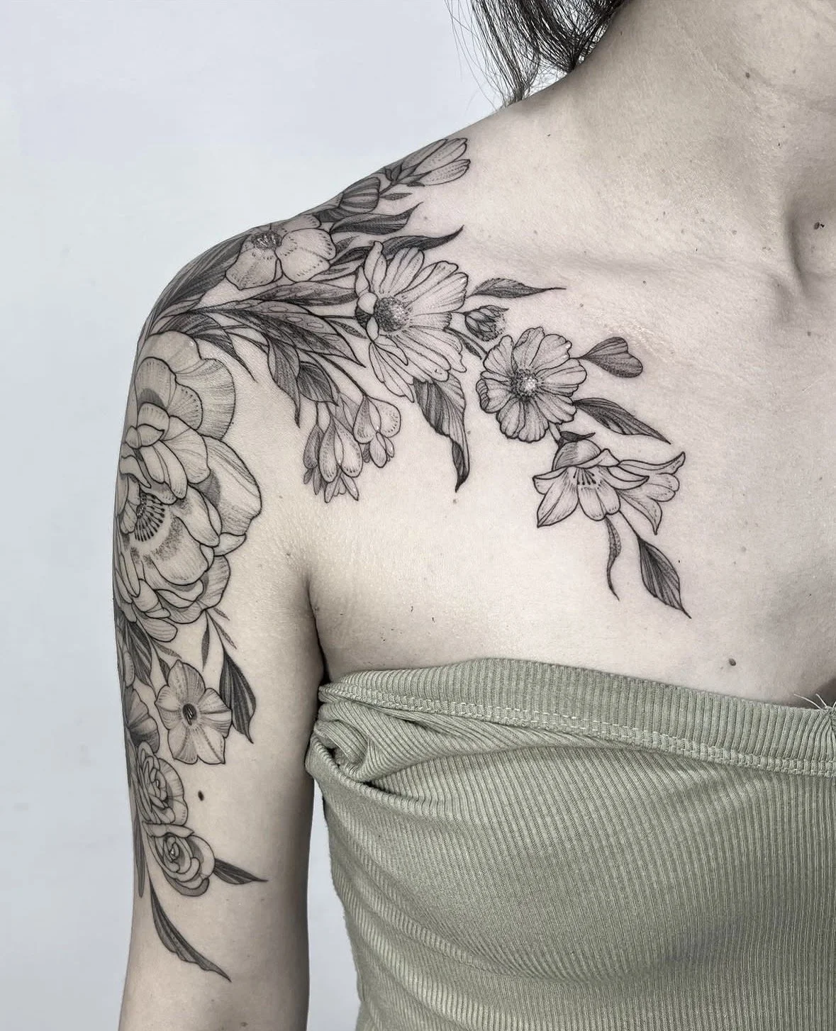 Tatuaje de flores en el hombro y brazo izquierdo de una persona.