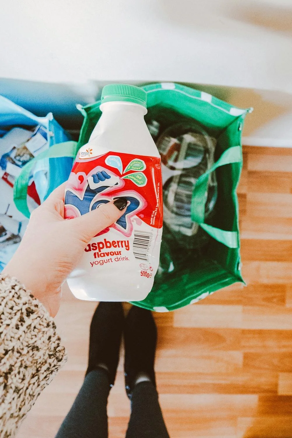 Hand placing plastic bottle into reusable bag for recycling