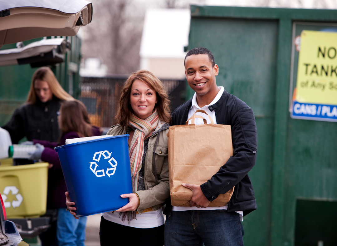 Two people holding containers at a recycling dropoff