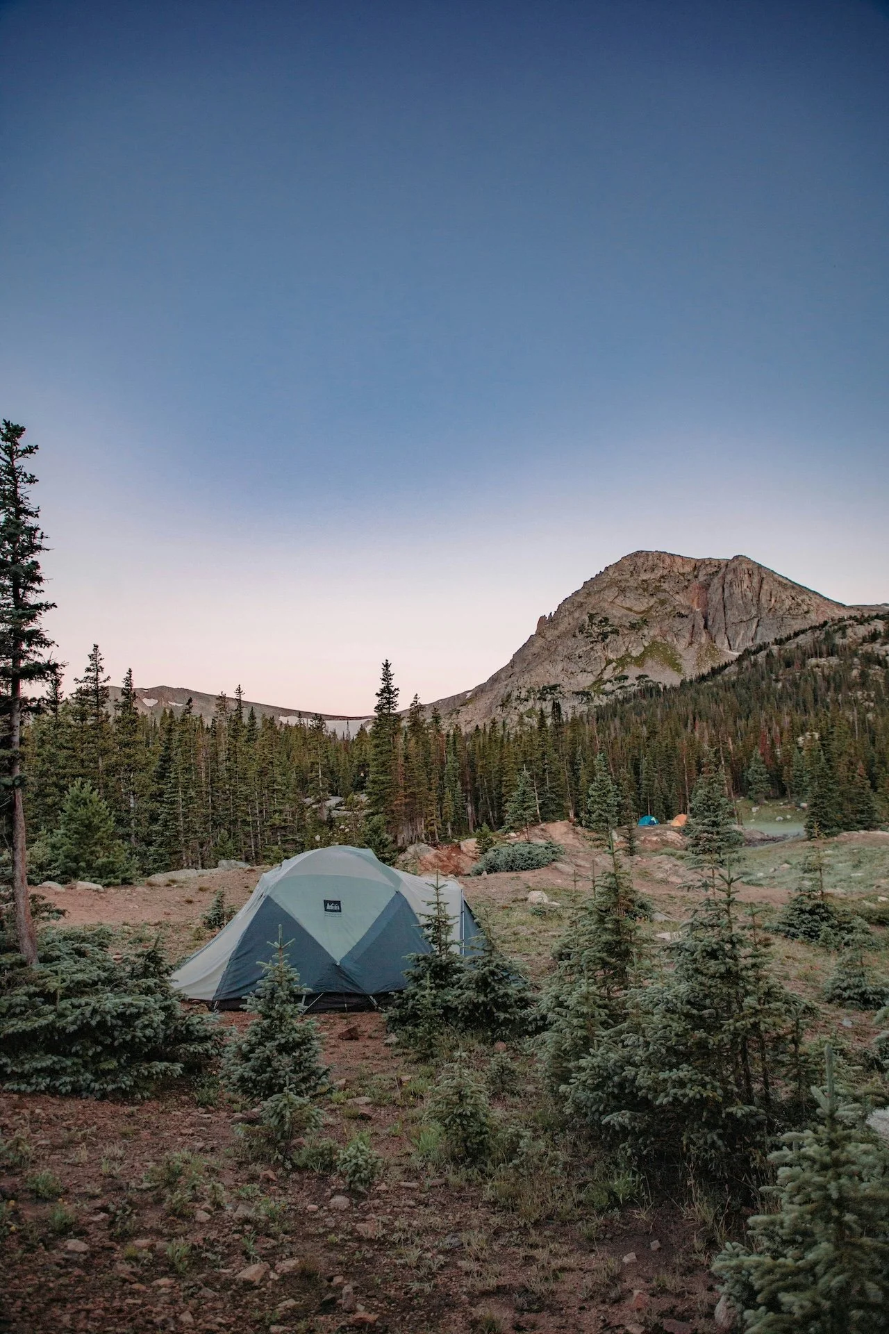 Tent set up in front of trees and mountains at sunrise