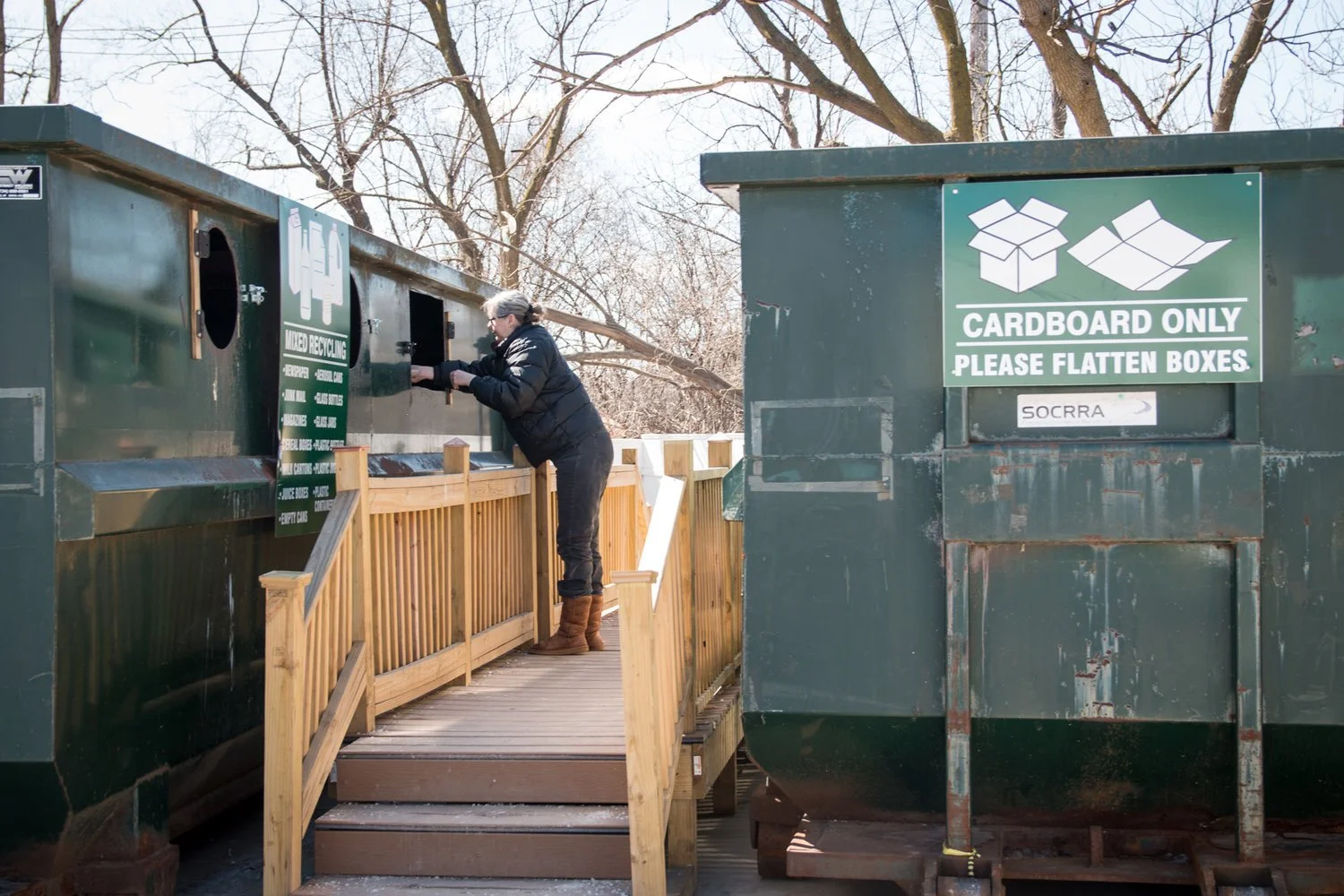 person putting recyclable materials into drop-off bin