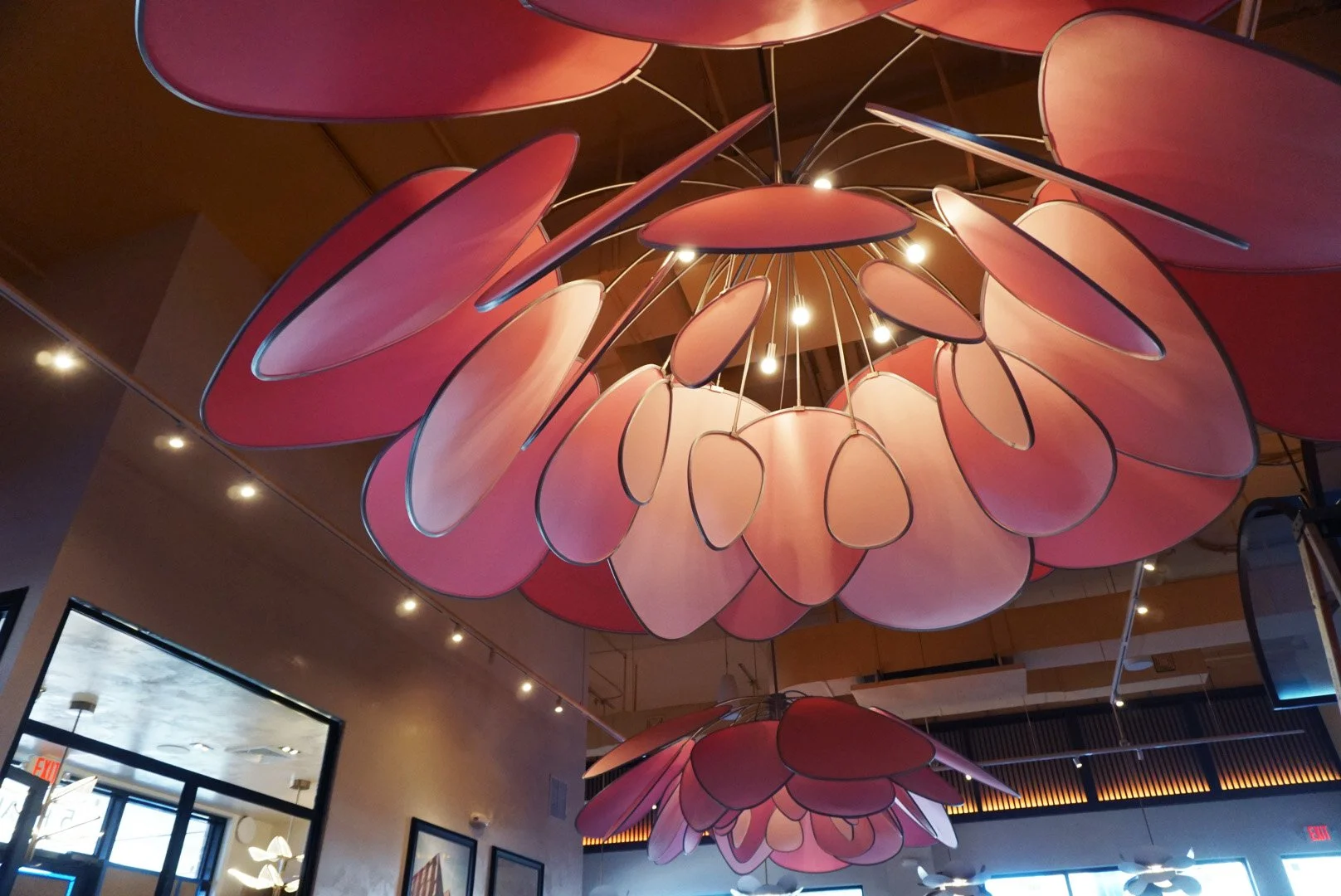 Modern pink floral chandelier hanging from ceiling in a restaurant or cafe.