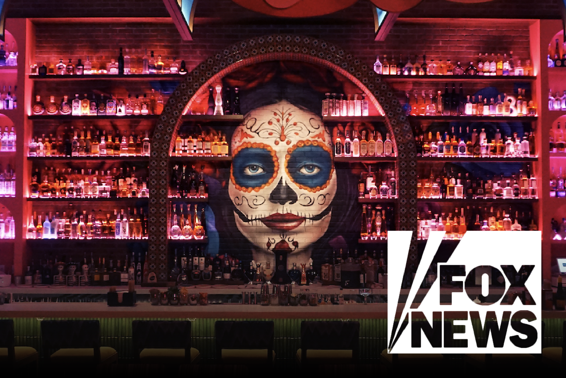 A mural of a woman with a sugar skull face painting, behind a bar with shelves of liquor bottles, in a dimly lit environment with pink and purple lighting. The Fox News logo is in the bottom right corner.