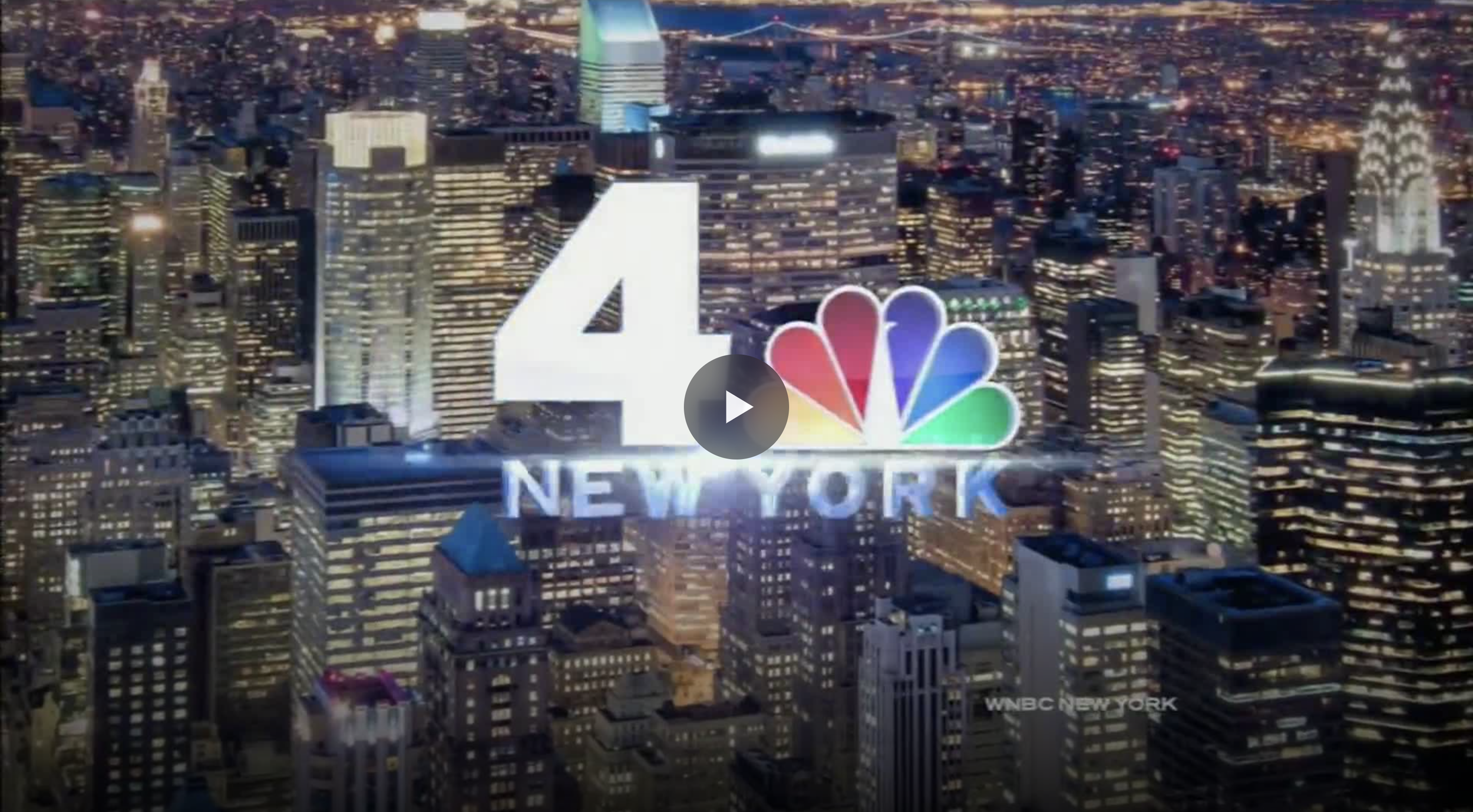 Nighttime aerial view of New York City skyline with illuminated skyscrapers, featuring large NBC logo and the number 4 over 'NEW YORK' in the center.