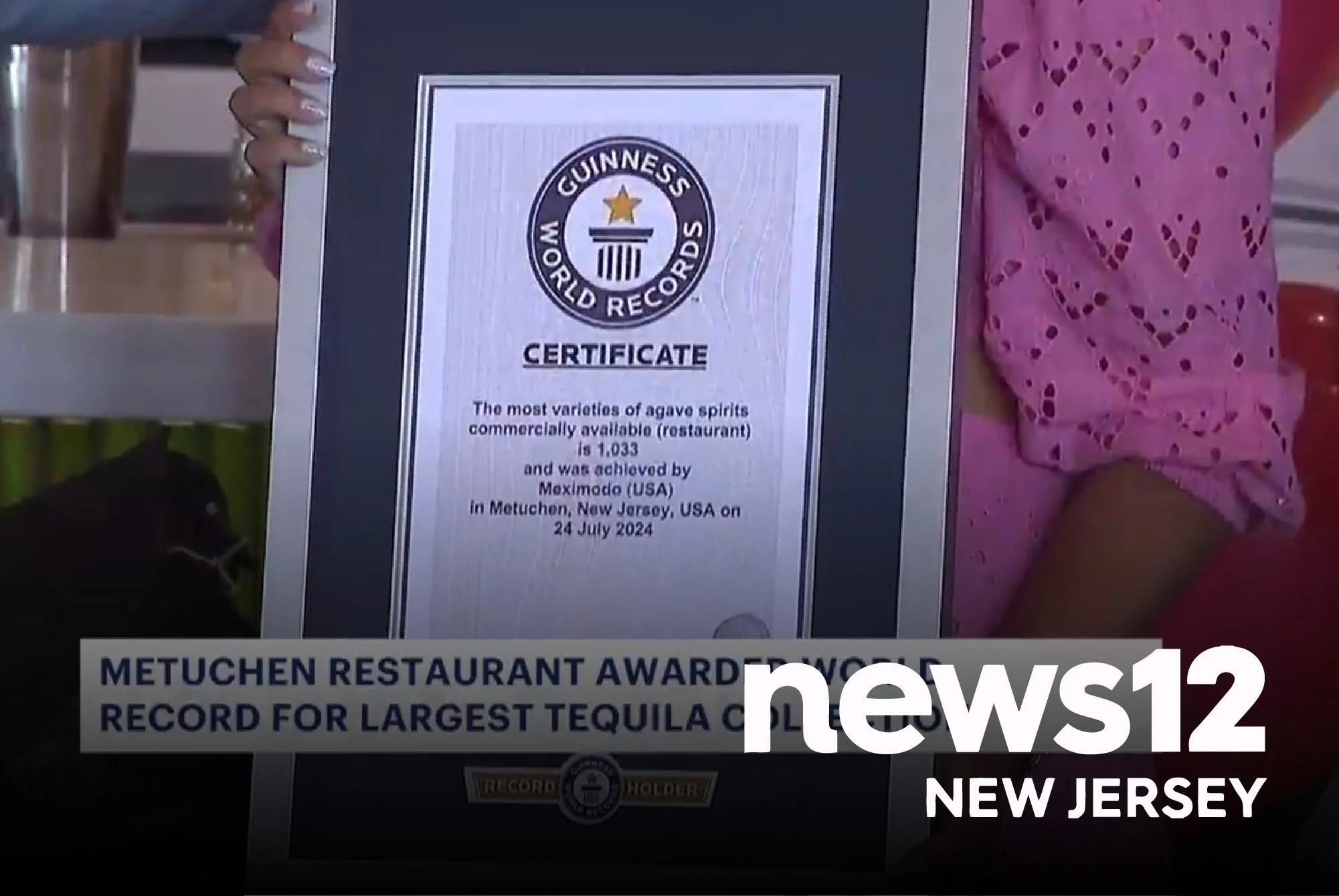 A person holding a Guinness World Records certificate for the largest tequila collection, awarded to Metuchen, New Jersey, USA. The certificate states the record for most varieties of agave spirits commercially available, achieved by Maximoado on July 24, 2024.
