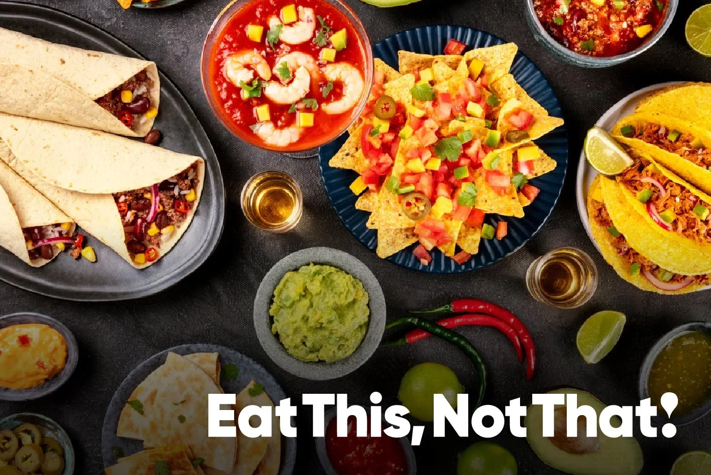 A variety of Mexican foods including tacos, guacamole, shrimp cocktail, nachos, tacos with lime, and various dips and salsas on a dark table.