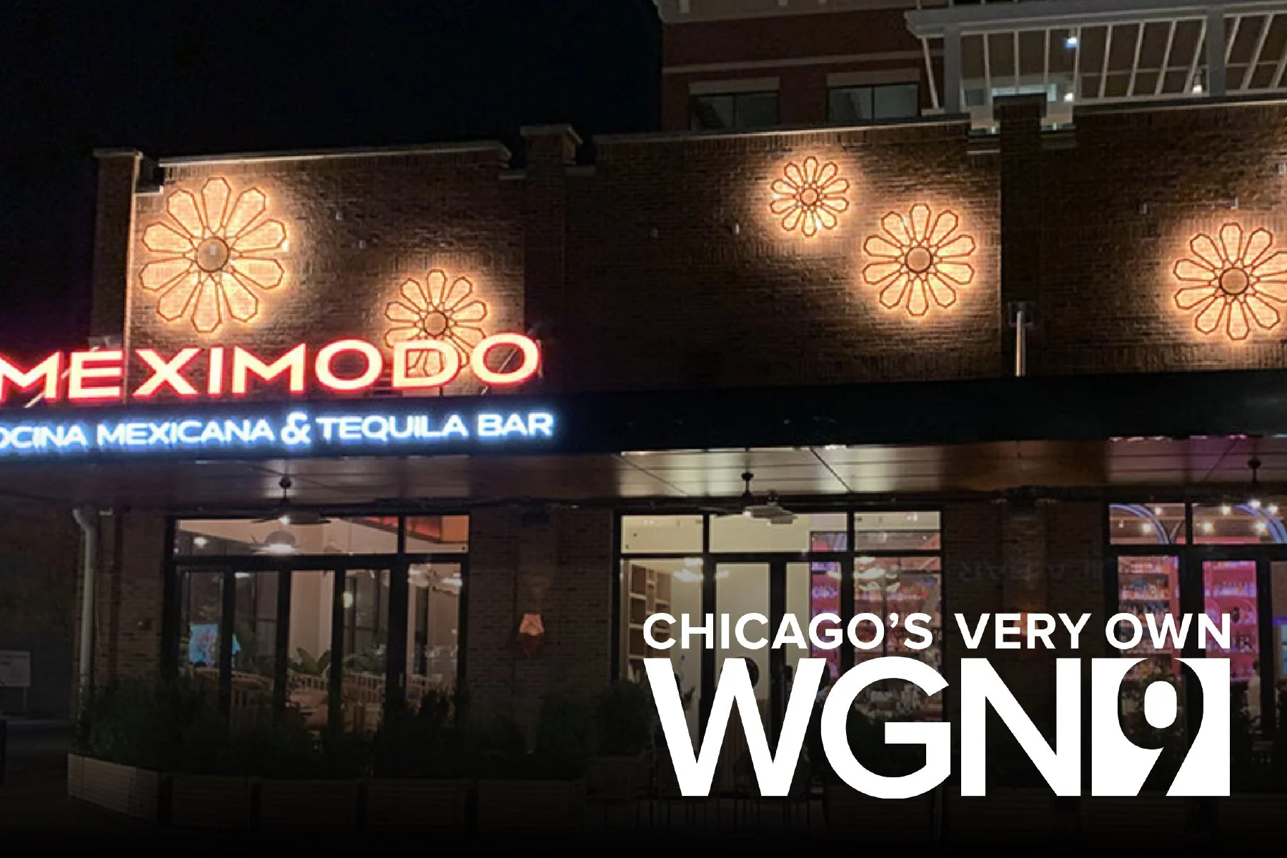 Nighttime exterior view of Meximodo, a Mexican restaurant and tequila bar in Chicago, with illuminated signage and decorative lights on the brick facade.