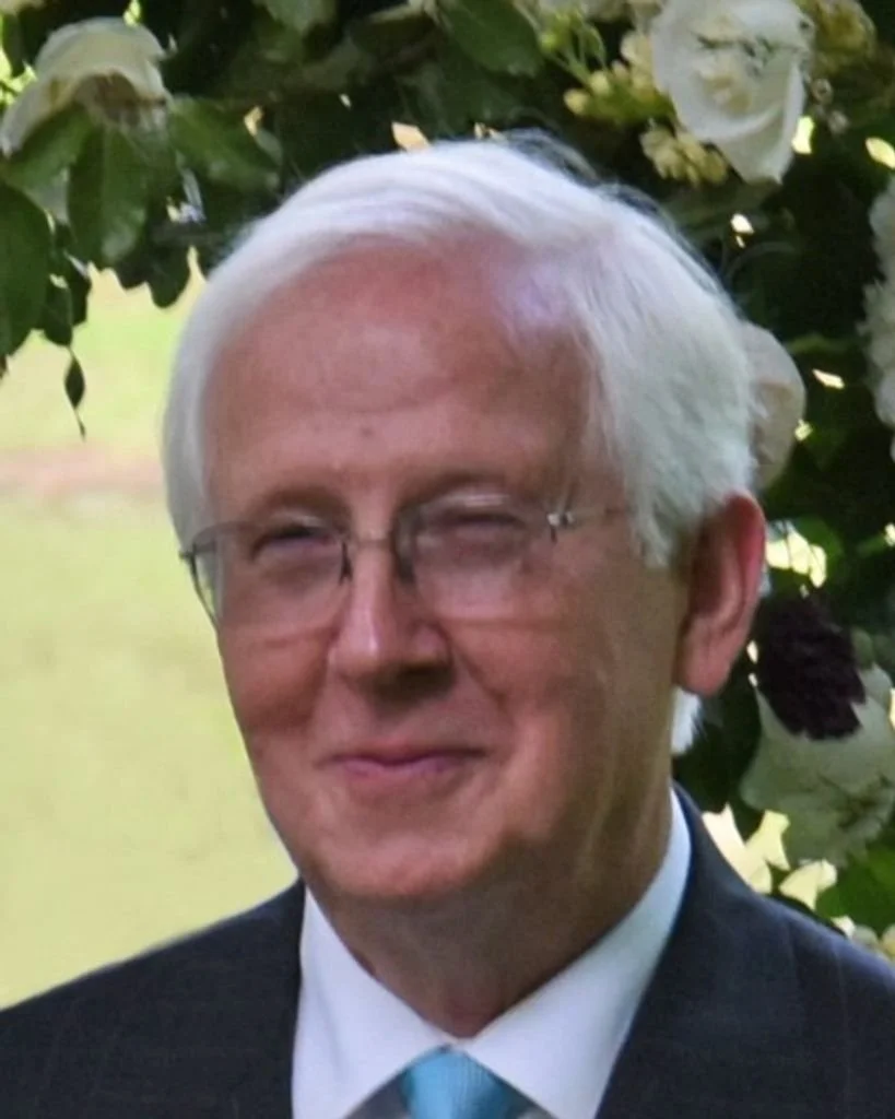 Mac Kelton wearing a suit and glasses.
