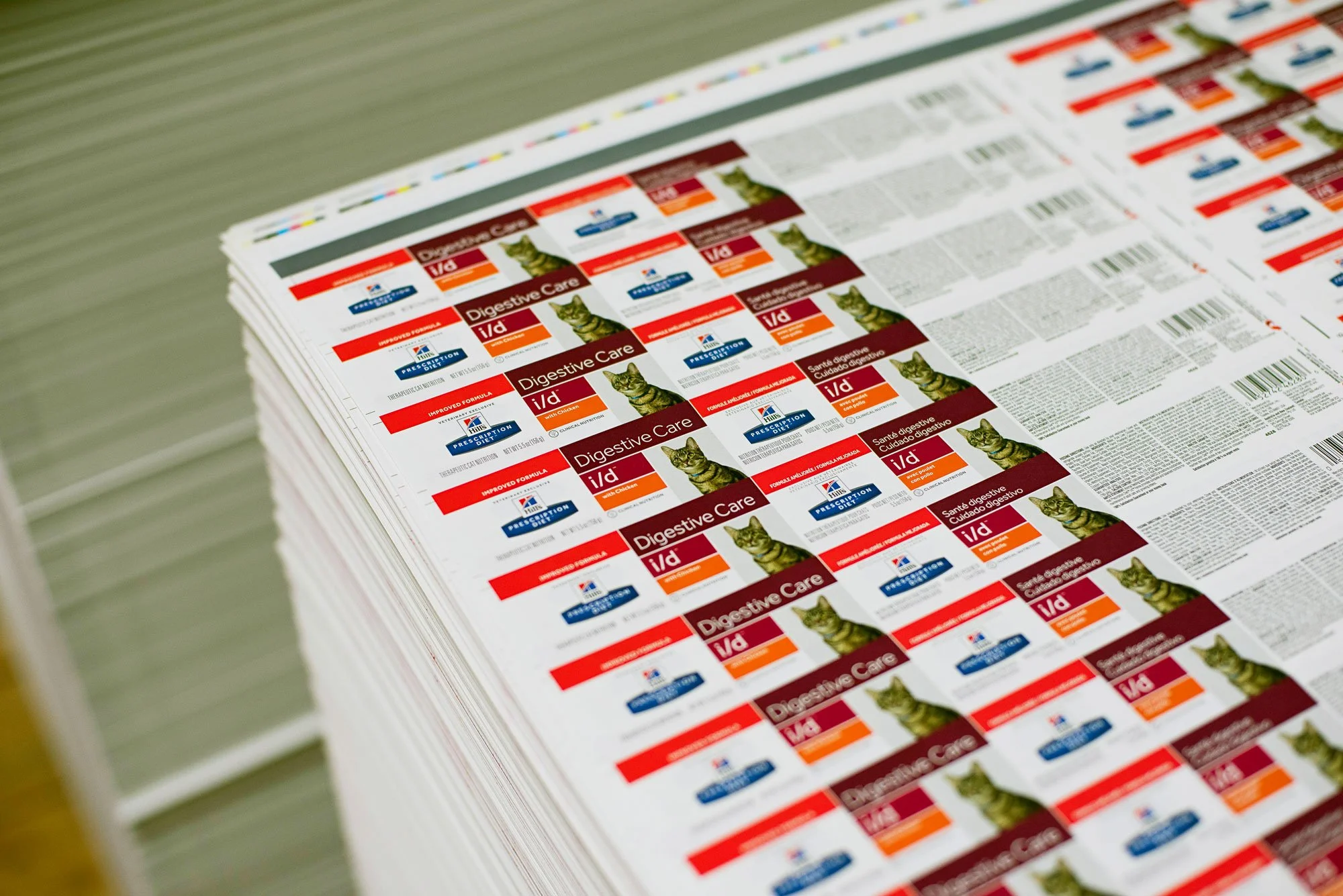 Stack of printed pet medication labels for digestive care, featuring a cat image and text, on a table.