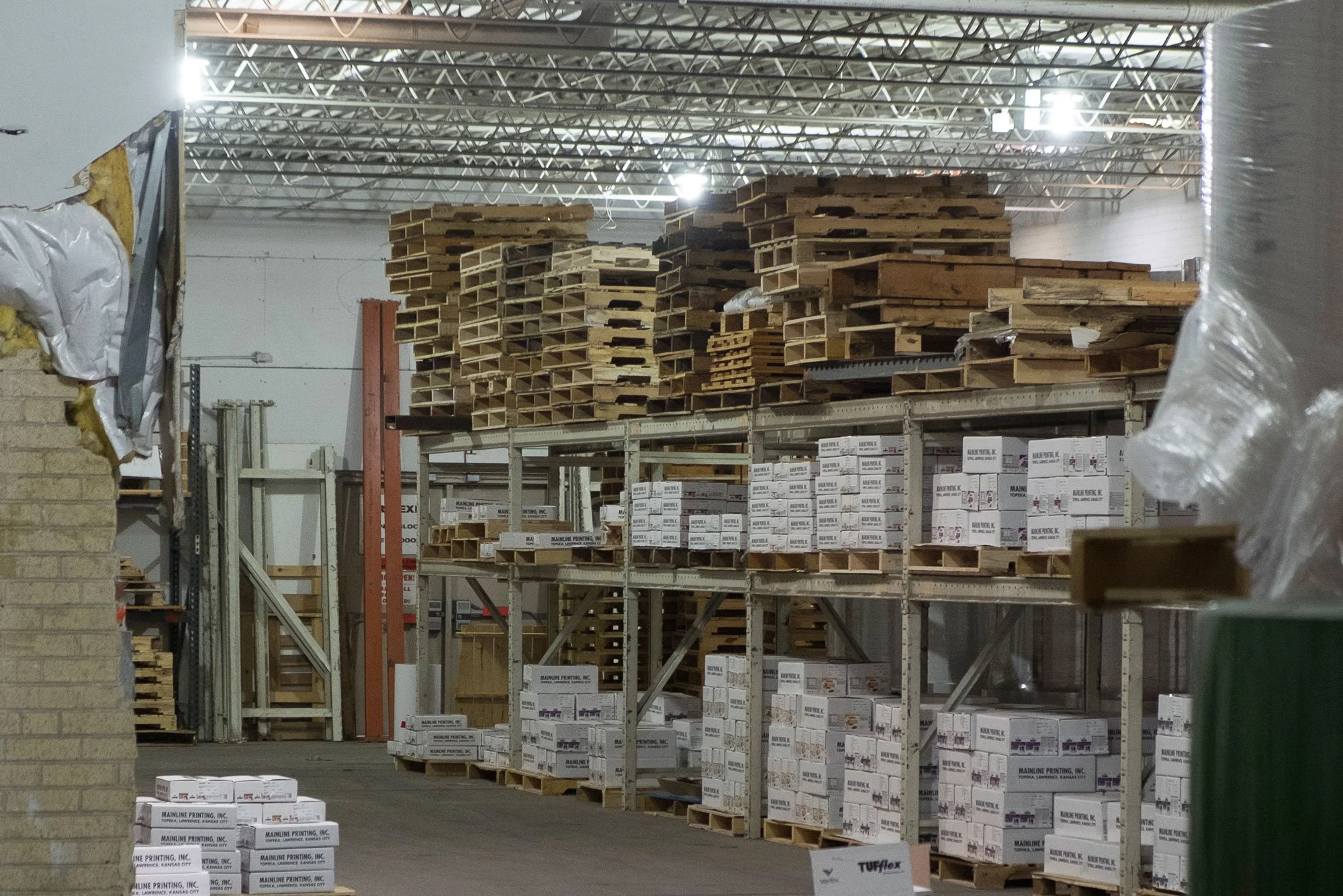 Warehouse Storage with stacked wooden pallets and cardboard boxes on metal shelving units.