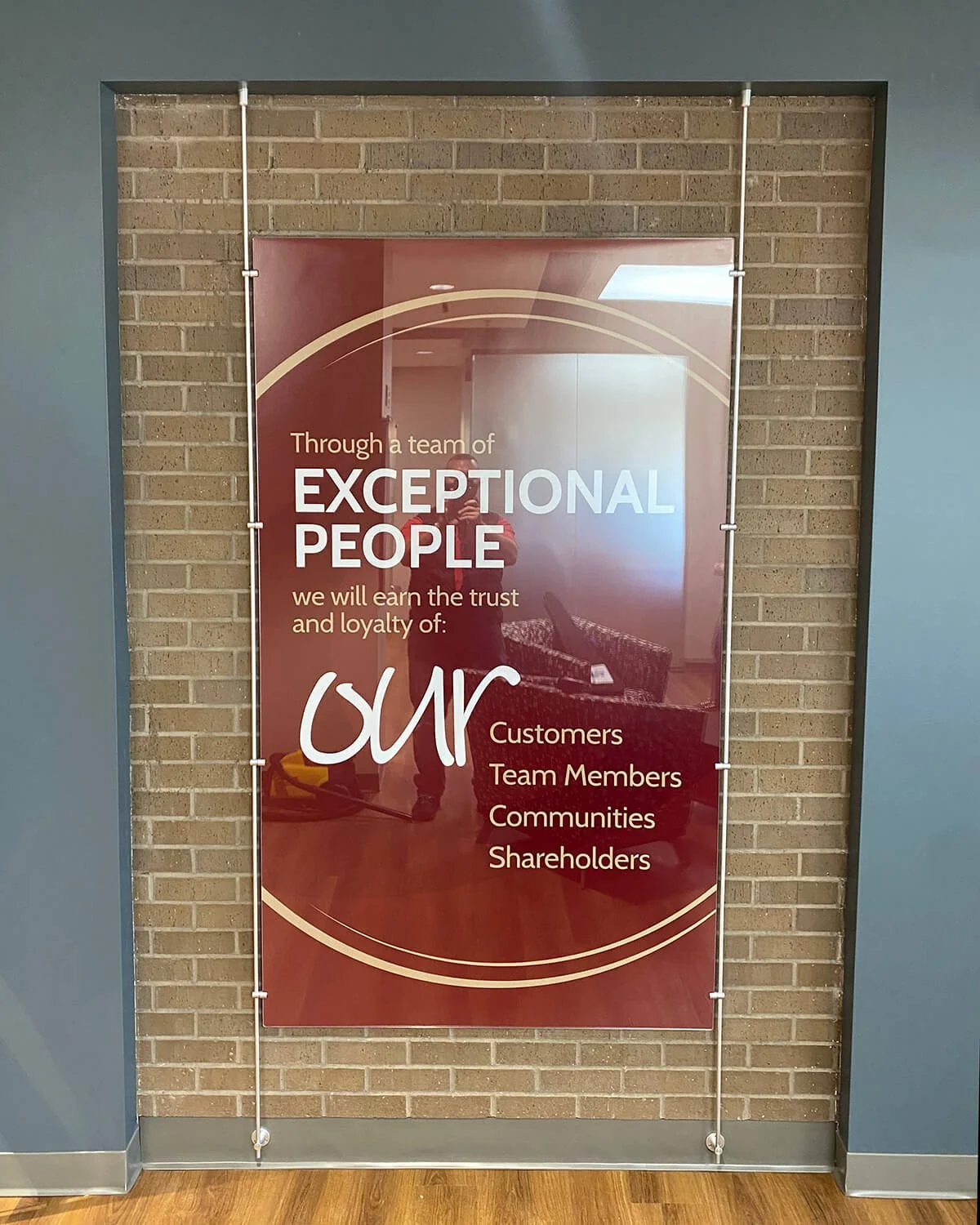 Sign on brick wall promoting company values about being exceptional and earning trust from customers, team members, communities, and shareholders.