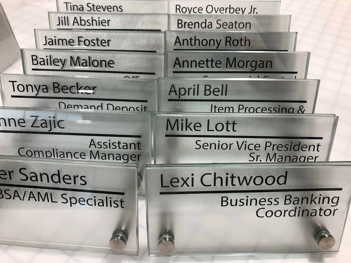 Printed name tags for bank employees arranged in a display holder.