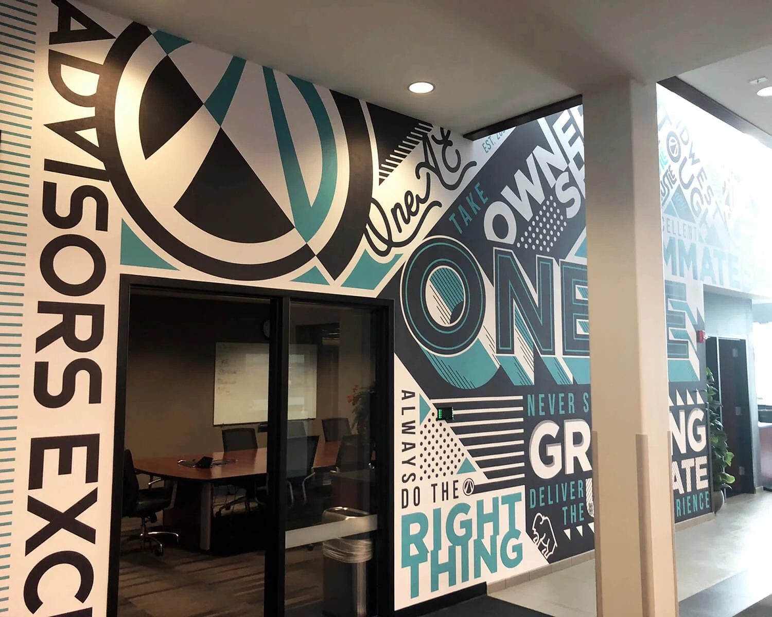 Colorful motivational wall art with words like "One," "Rights," "Always," "Do the right thing," and "Never give up" in a modern office building hallway.