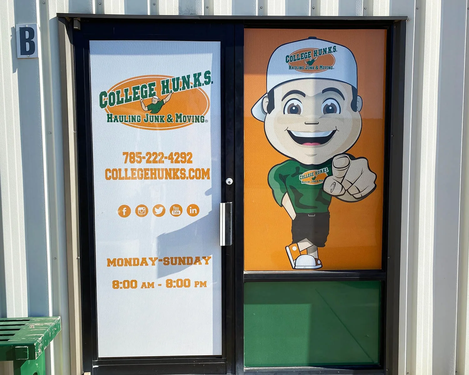 Sign for College Hunks Hauling Junk & Moving with contact information and a cartoon mascot pointing.