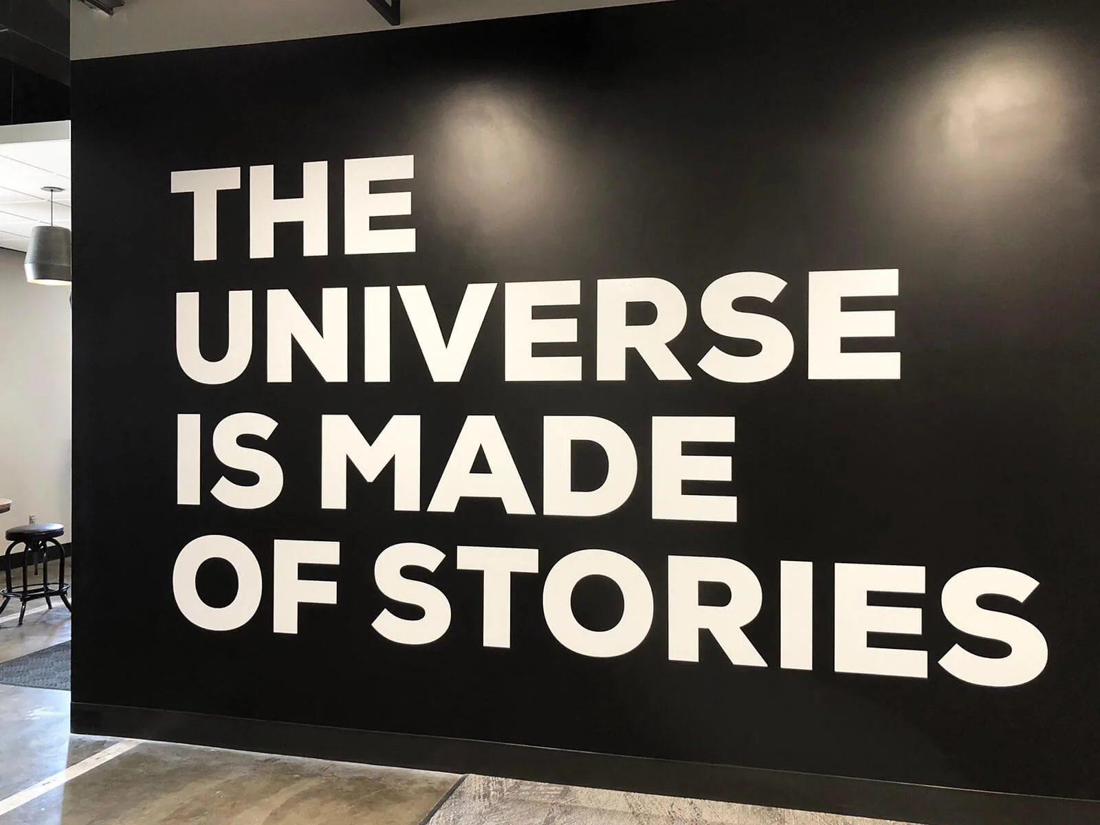 A black wall with large white text that reads, 'The universe is made of stories'.
