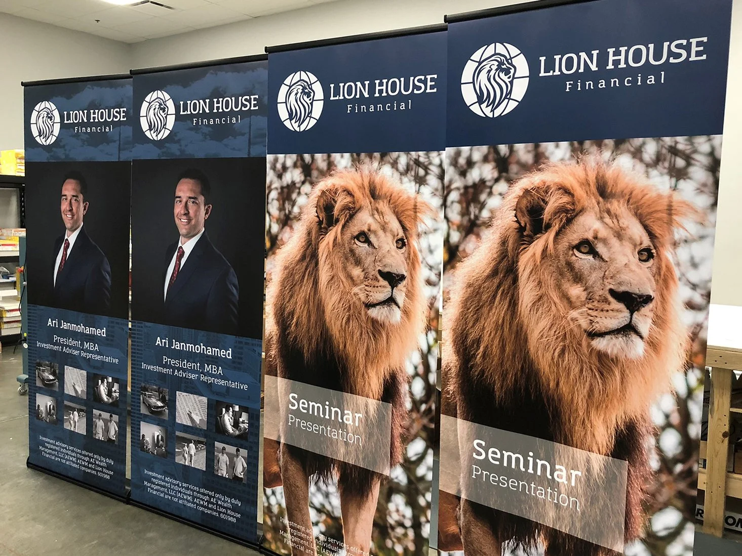 Three retractable banners for Lion House Financial. The first two feature a man in a suit and tie with the text 'Ari Janmohamed, President, MBA, Investment Advisor Representative.' The third banner displays a lion with a mane and the text 'Seminar Pr