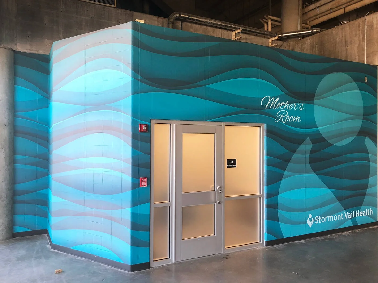 Underground health clinic labeled 'Mother's Room' with blue wave-patterned walls and a door with frosted glass panels, part of Stormont Vail Health facilities.