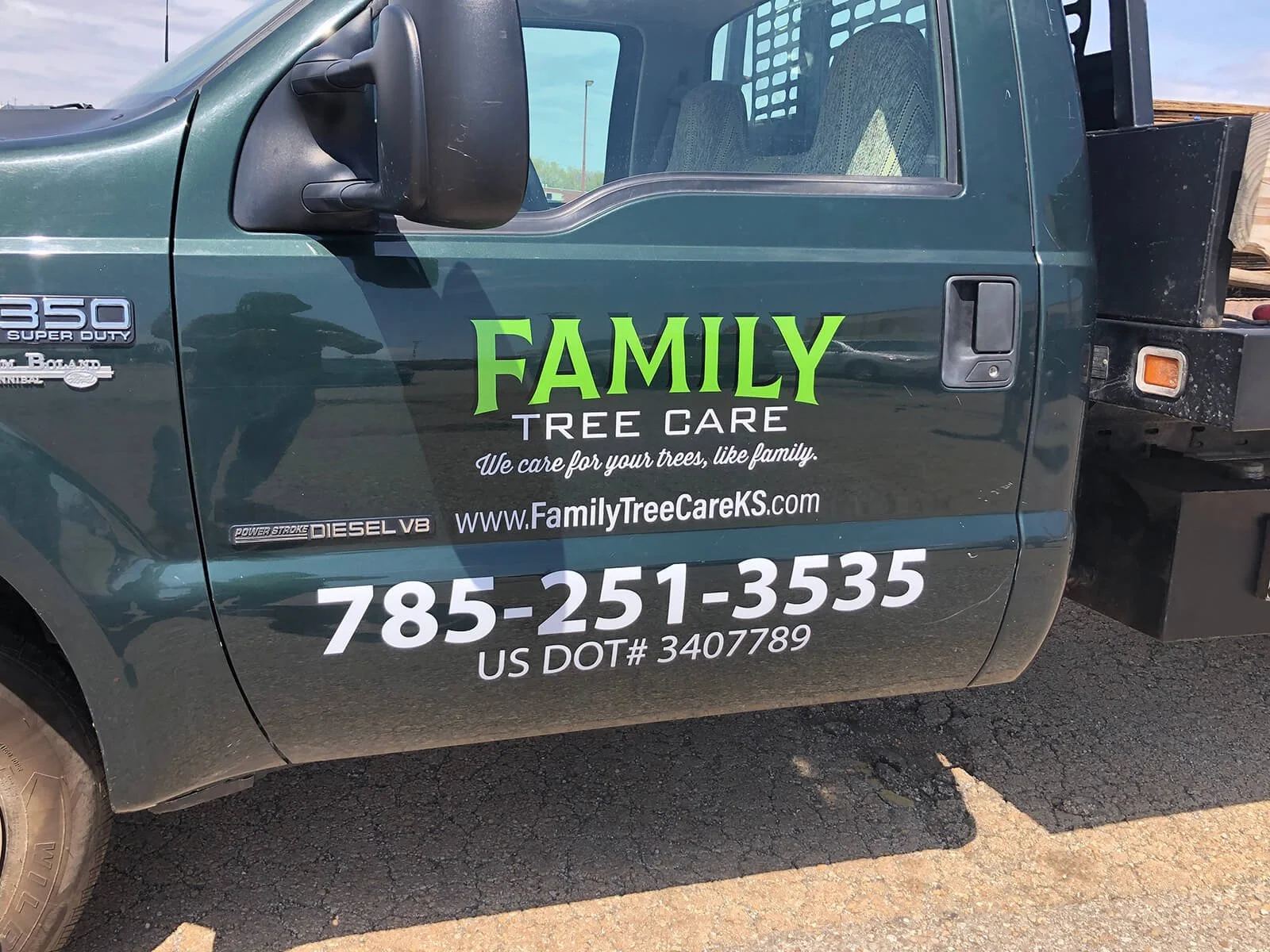 A green work truck with Signage for Family Tree Care, a tree care company. The text includes the company's website, phone number, and a slogan about caring for trees like family.