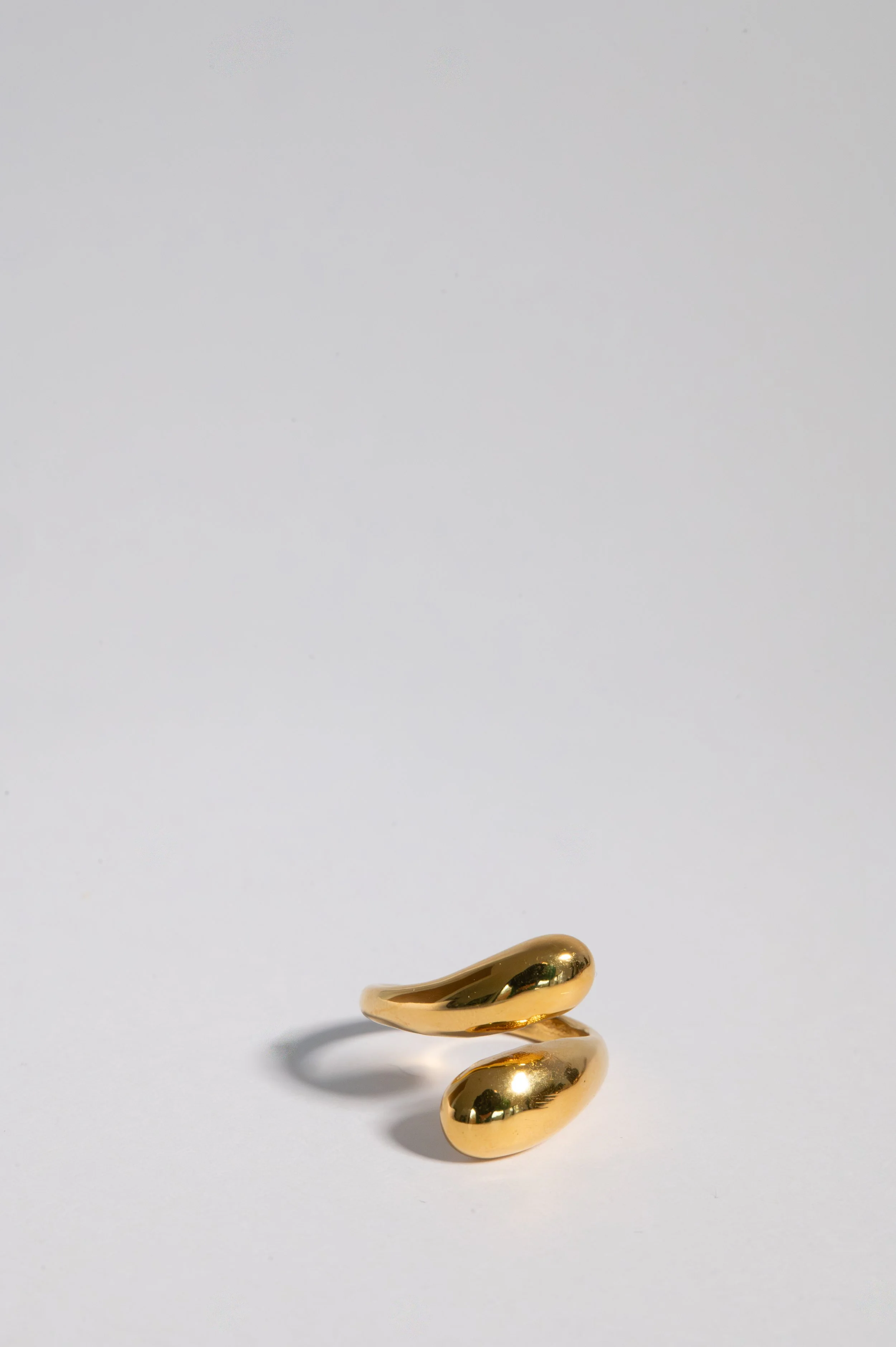 A gold ring with a modern, abstract design displayed on a white surface.
