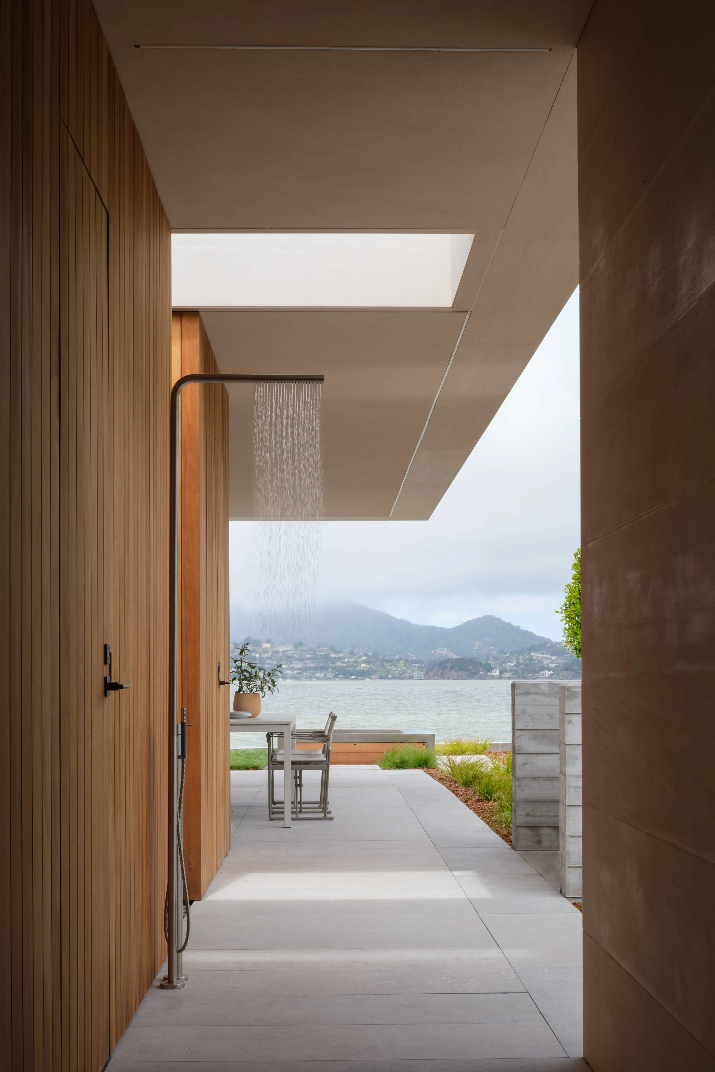 Modern Tiburon waterfront outdoor shower with warm wood panel walls and an open view to the bay, creating a private wellness moment that supports indoor outdoor living in Marin County.