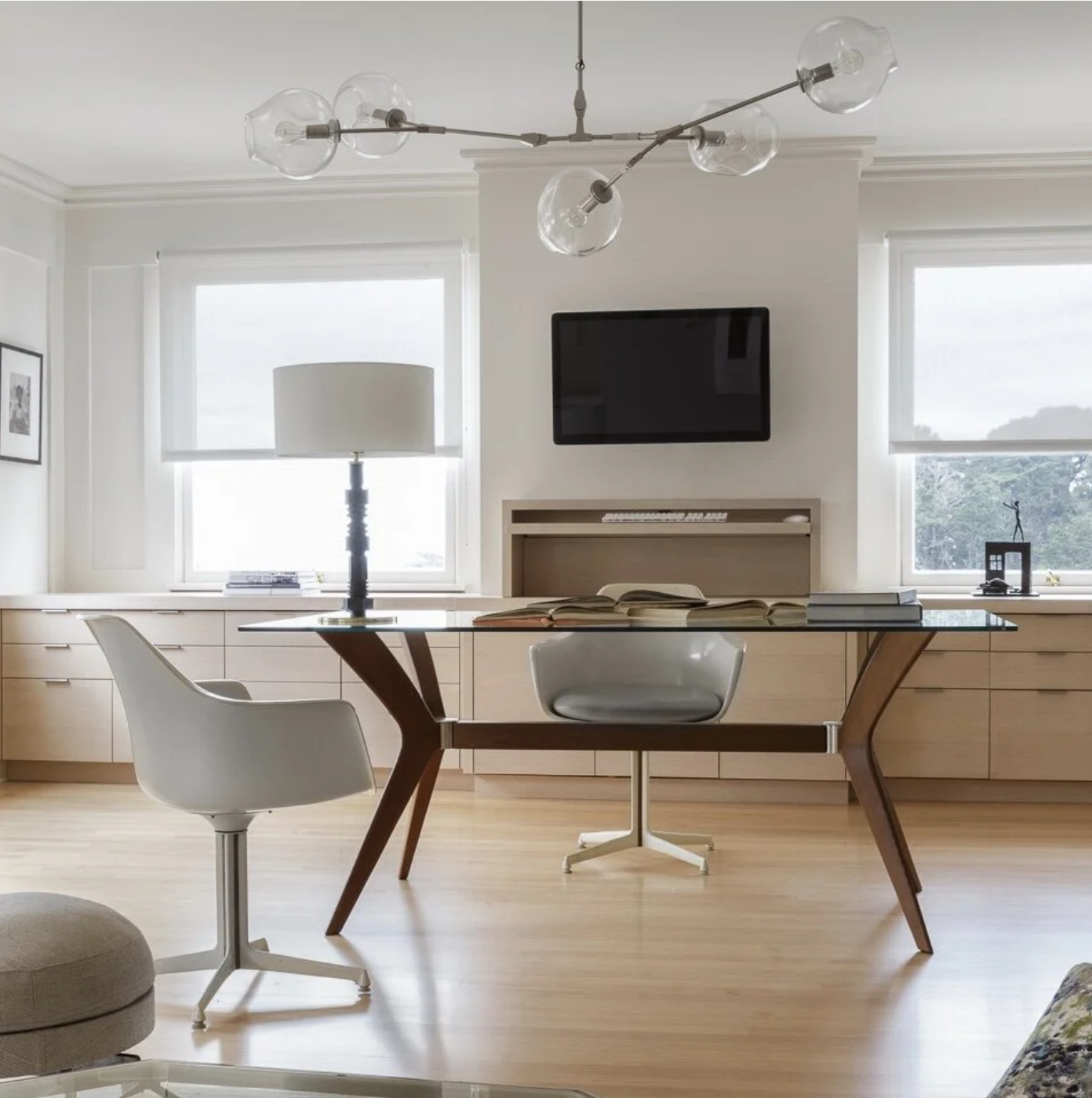 Modern home office with a wood desk and ergonomic chairs, styled with a sculptural art installation, task lighting, and large windows with blinds, creating a calm, functional workspace in a luxury residence.