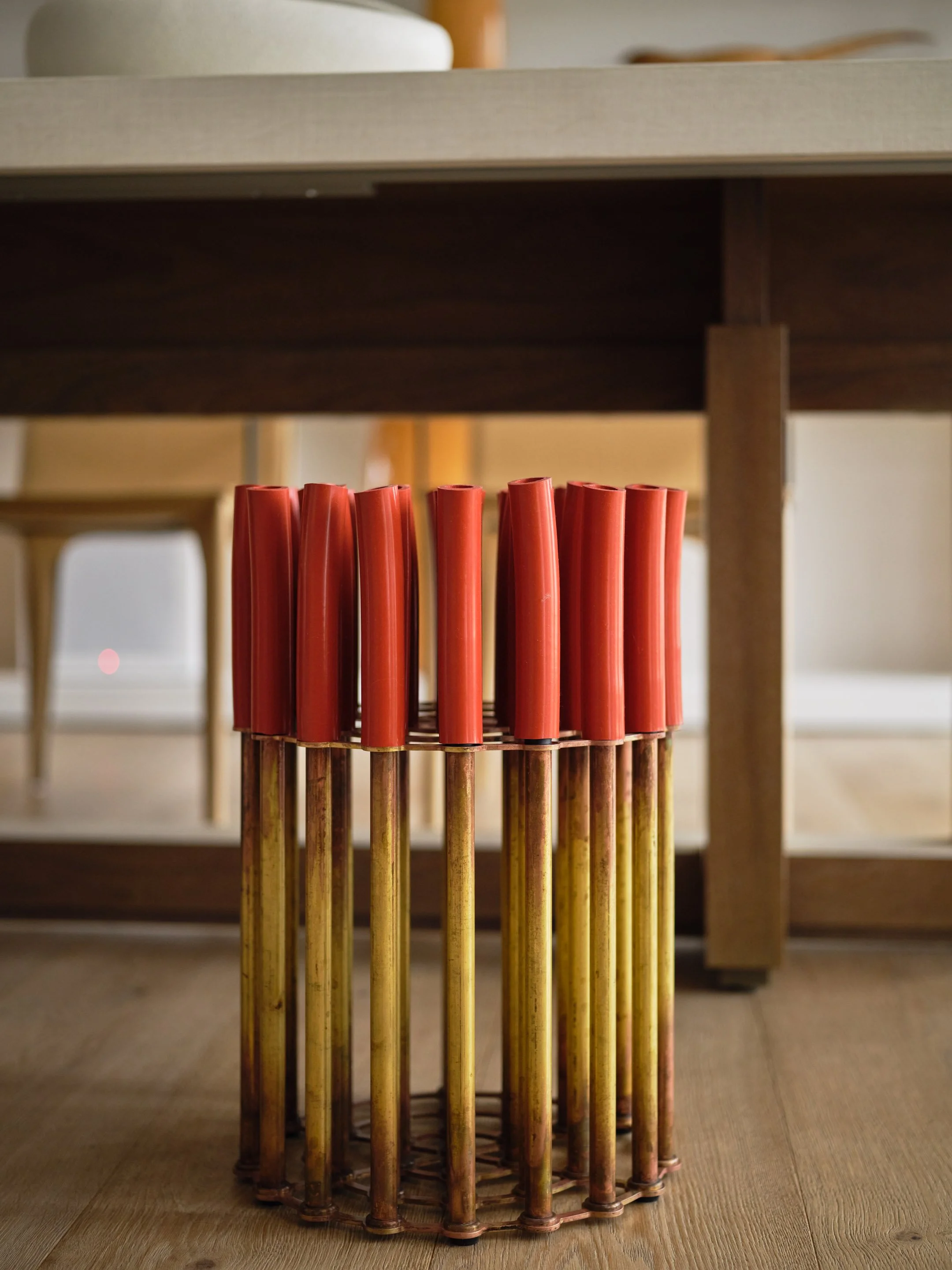 Broadway Penthouse Pacific Heights custom magazine rack in warm wood with vertical brass rods and red leather handles, adding a crafted modern detail to a calm luxury San Francisco interior.