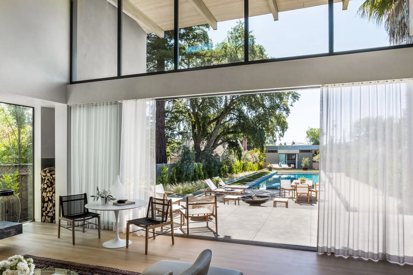St. Helena Napa Valley living room with large sliding glass doors opening to the backyard pool, connecting indoor seating to outdoor lounge chairs and lush garden views for relaxed luxury indoor outdoor living.