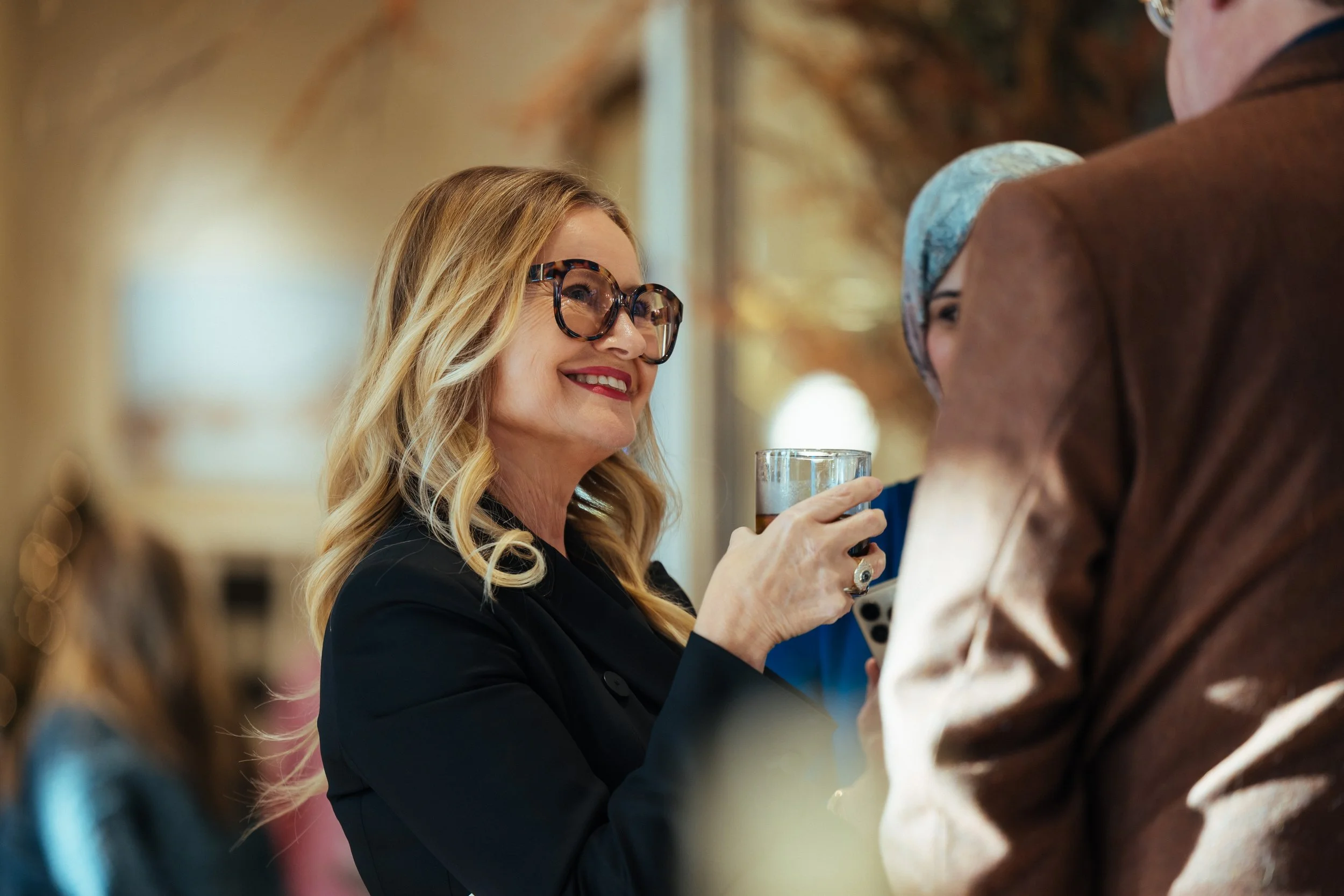 Sabra Ballon speaks with guests at a Palo Alto design event, smiling while holding a drink, representing ballonSTUDIO’s luxury interior design community and leadership in Bay Area residential design.