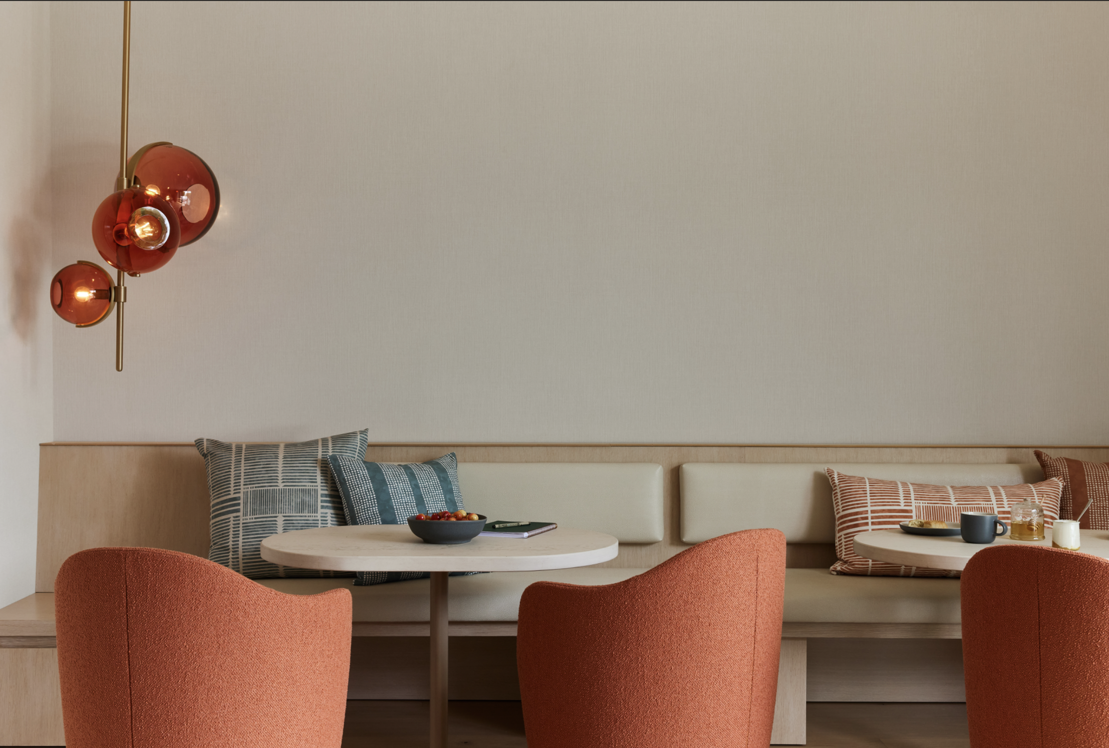 Union Street Marina District dining nook in San Francisco with upholstered banquette and salmon chairs around a round white table, styled with patterned pillows and a sculptural wall light for modern luxury interior design.