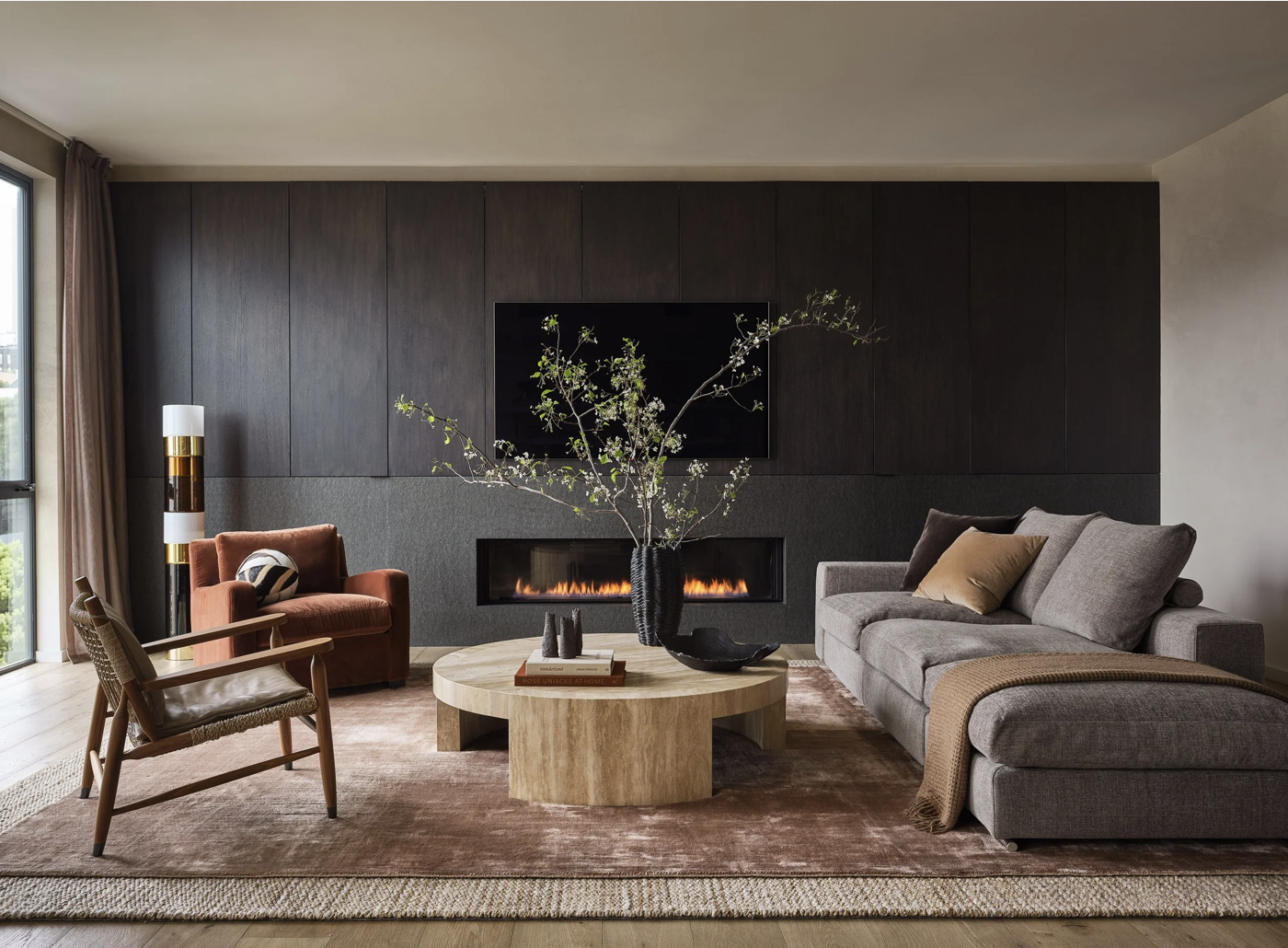 Open plan San Francisco penthouse living and dining room with pale oak kitchen, sculptural branch arrangement, custom shelving, and warm modern furnishings in soft natural light