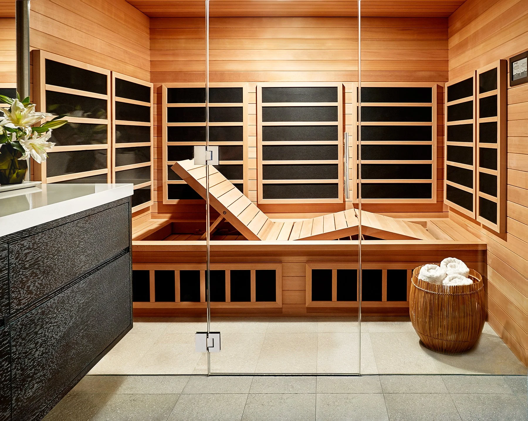 Custom red cedar infrared sauna behind glass with built in bench and warm lighting, designed as a private wellness retreat inside a Cow Hollow residence