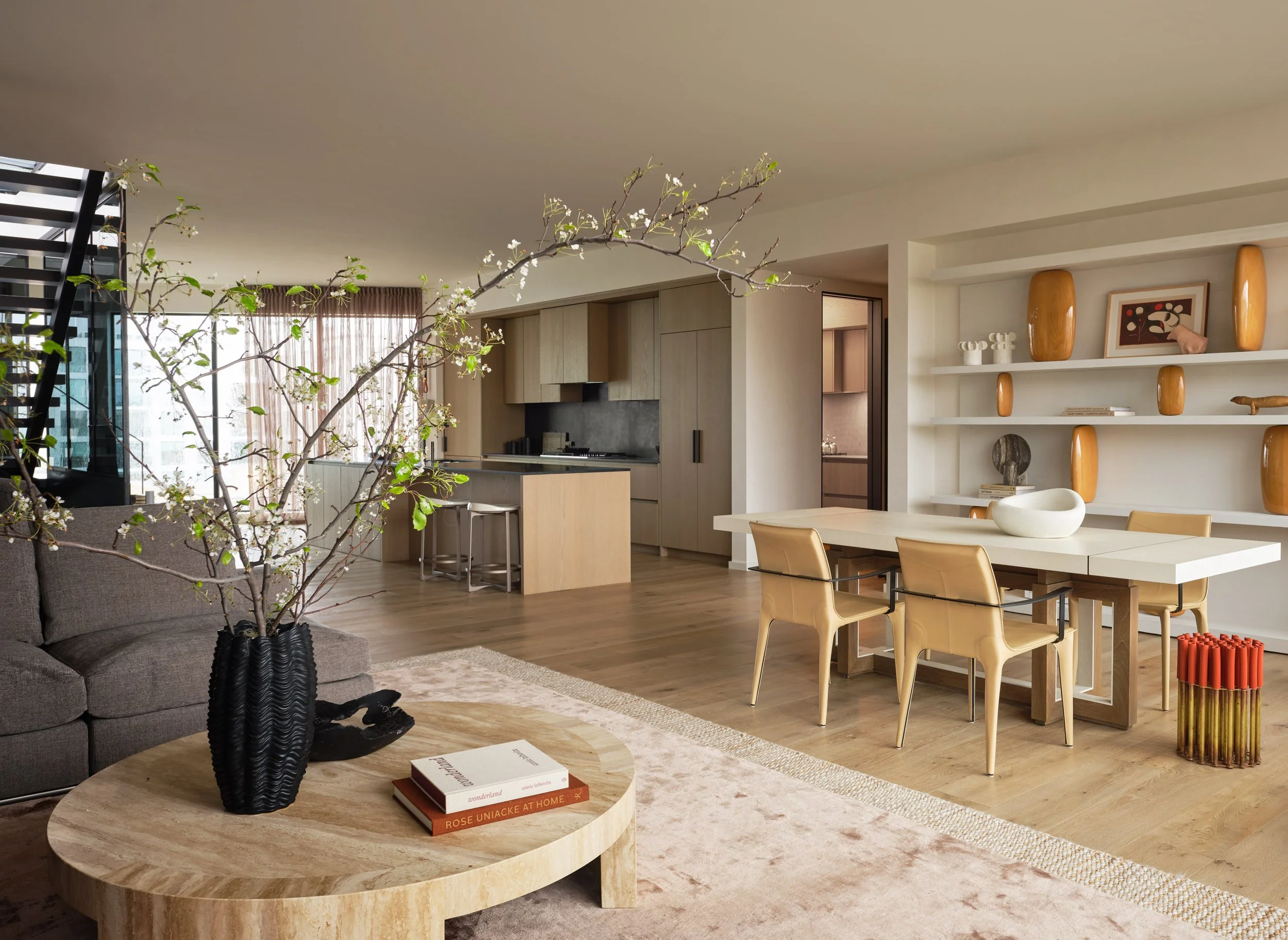 Broadway Penthouse Pacific Heights open concept living room and kitchen with pale wood furnishings, curated vases and art, soft drapery, and large windows that bring in San Francisco light for calm modern luxury interior design.