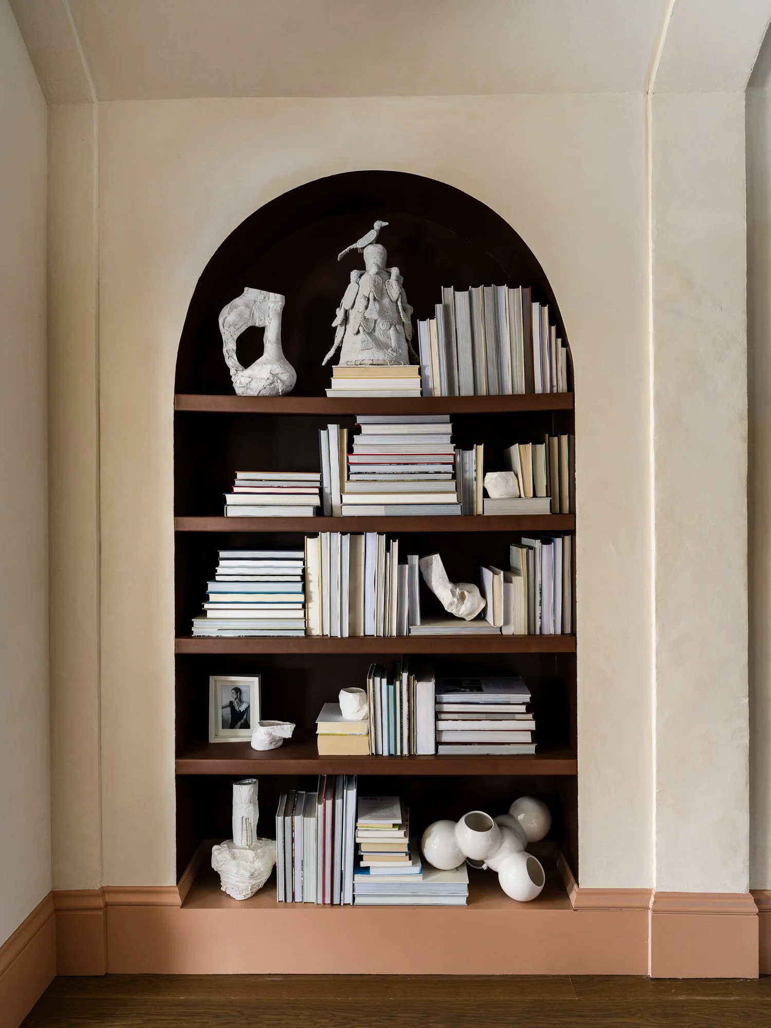 Built in bookshelf styled with sculptural objects and a framed photograph, set against warm beige walls and wood floors, reflecting ballonSTUDIO’s calm luxury interior design sensibility in San Francisco.