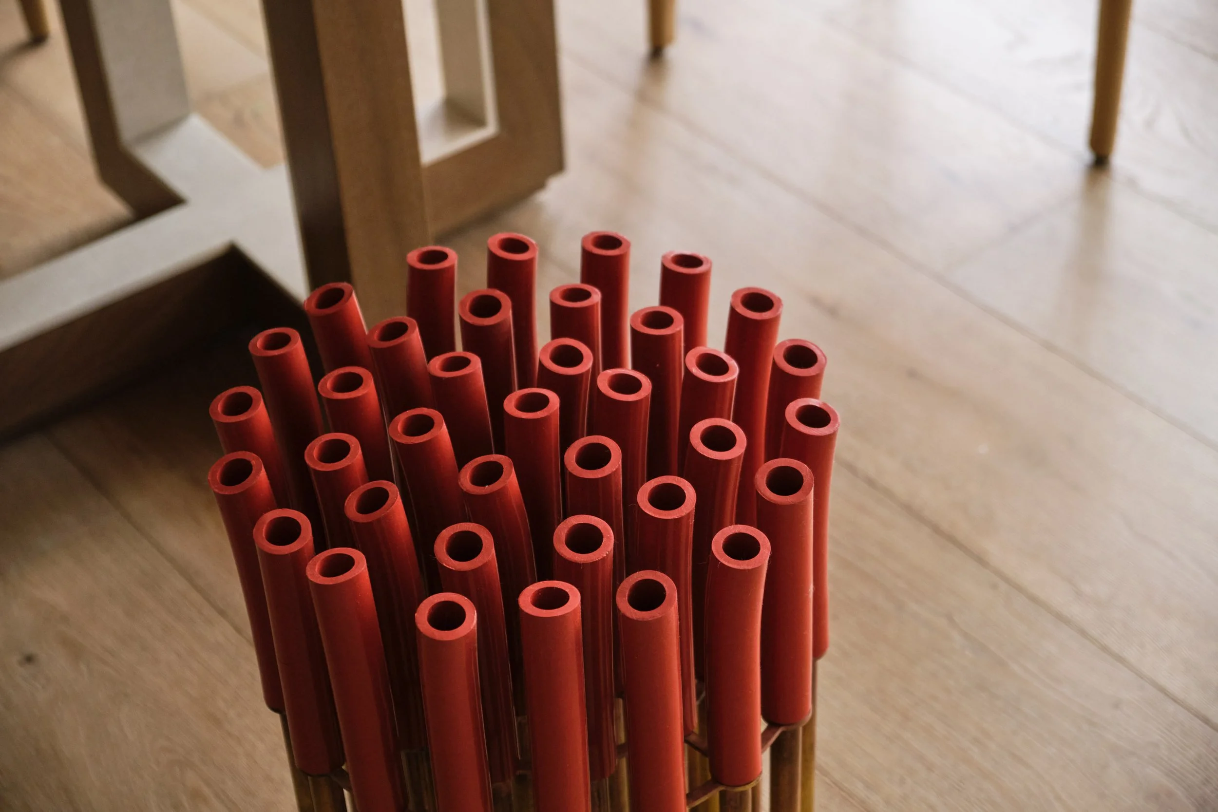 Broadway Penthouse Pacific Heights styling detail showing a cluster of red straws in a bamboo container on warm wood floors, adding a playful modern accent within a calm luxury San Francisco interior.