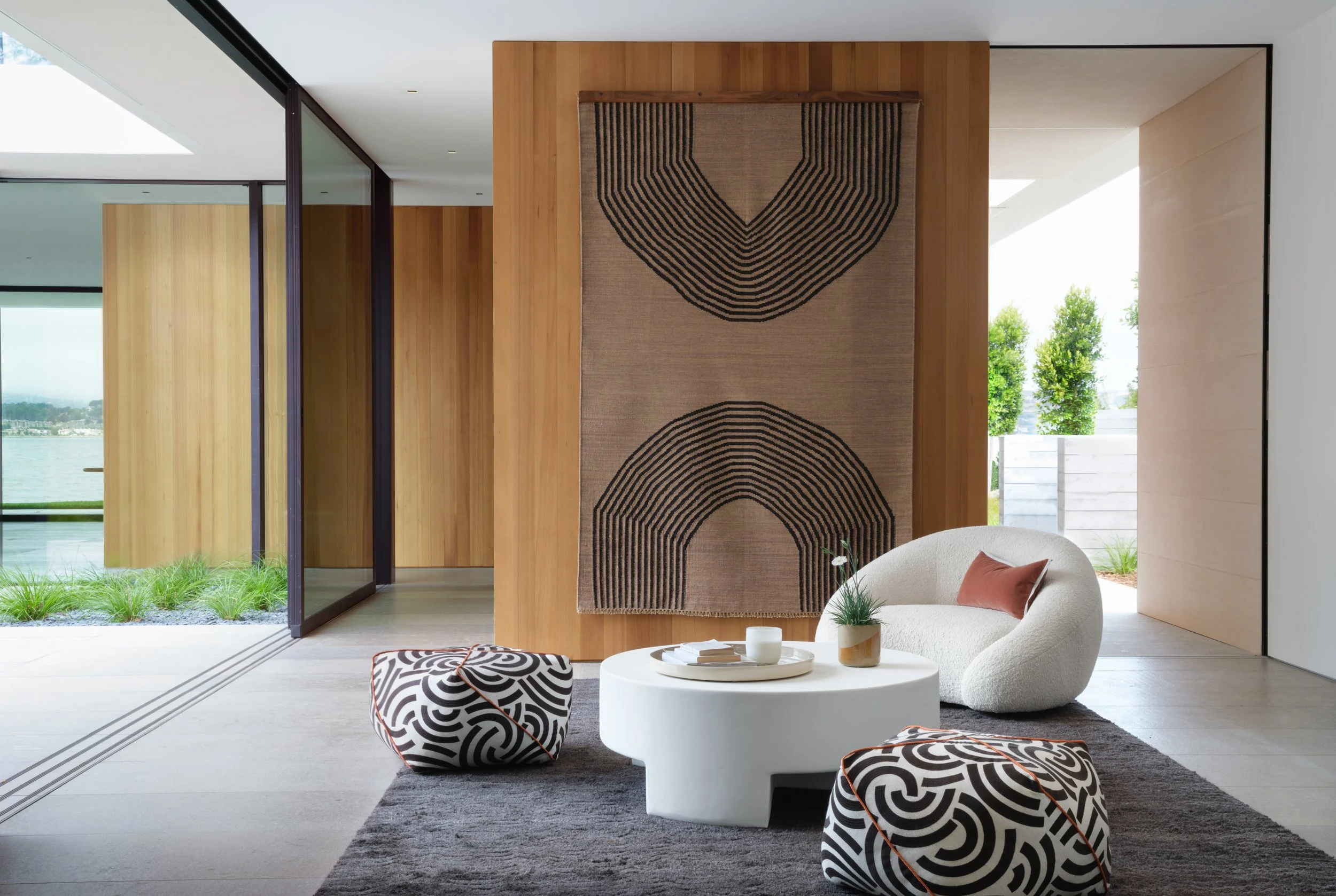 Minimal courtyard entry with vertical wood siding, large wood gate, and sculptural wall art, expressing Scandinavian simplicity and clean modern architecture in Tiburon waterfront home.